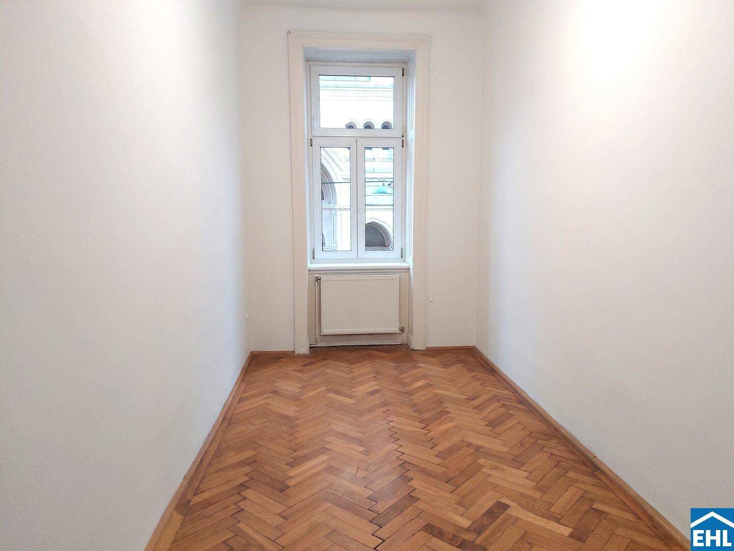 Kleineres Zimmer mit Fischgrätparkett und einem Fenster, ideal als Schlaf- oder Arbeitszimmer.