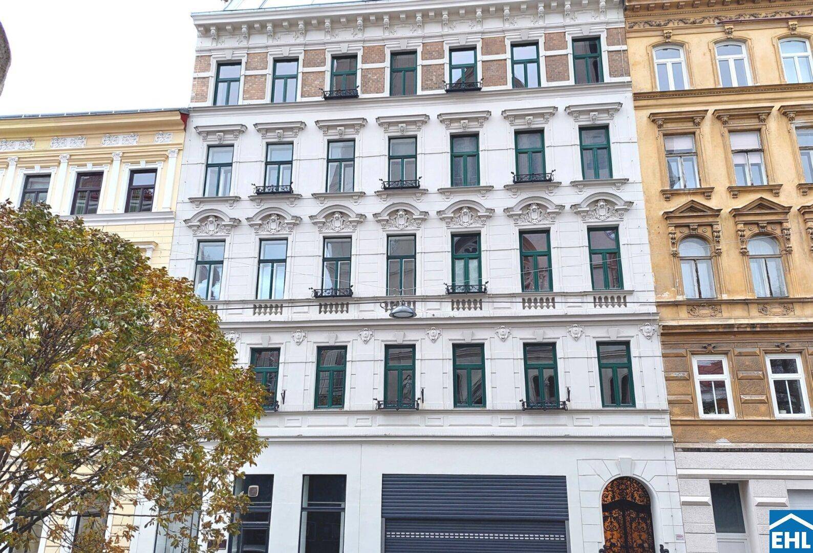 Historisches Mehrfamilienhaus mit reich verzierter Fassade und grünen Fensterrahmen.