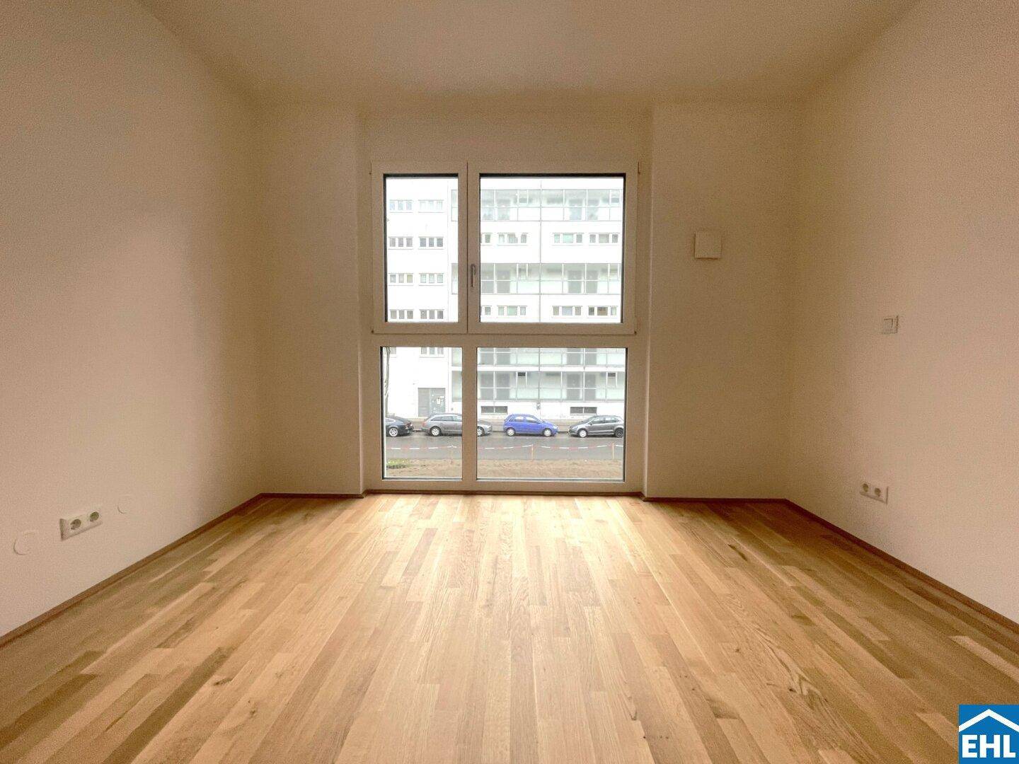 Geräumiges, leeres Zimmer mit großen Fenstern und Parkettboden, bietet viel natürliches Licht.