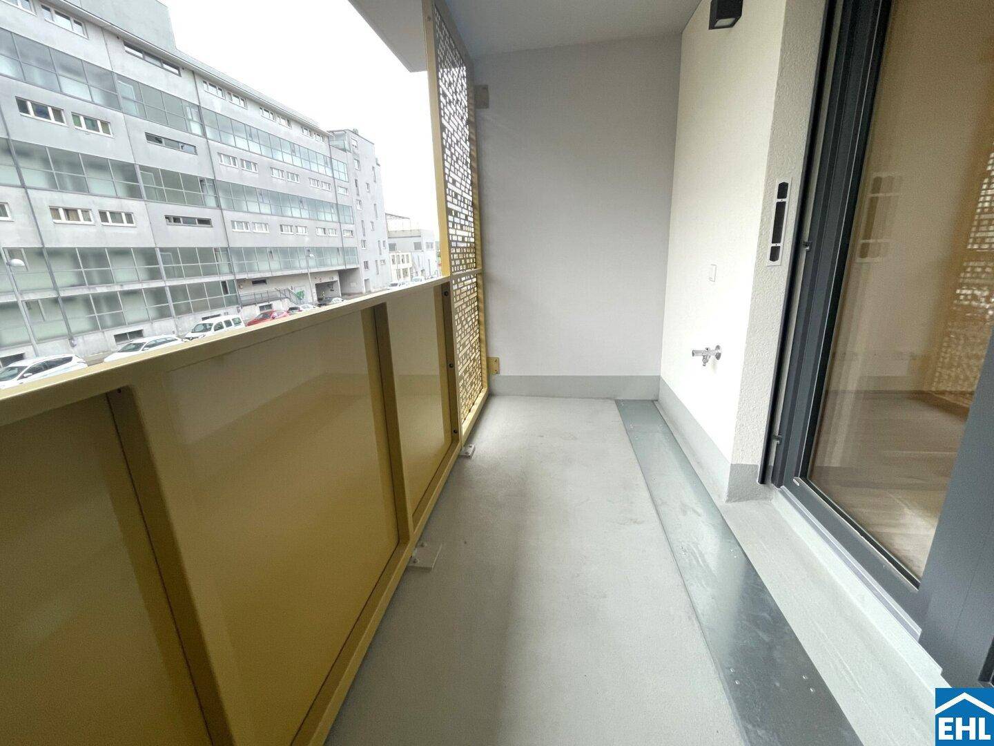 Schmaler Balkon mit gelben Sichtschutzwänden und Blick auf die angrenzenden Gebäude.