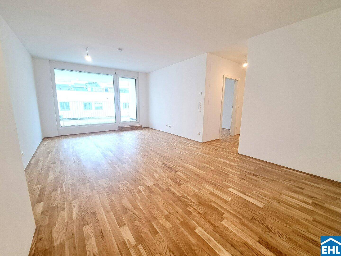 Helles, leeres Wohnzimmer mit großen Fenstern und hochwertigem Parkettboden, bereit zur individuellen Gestaltung.