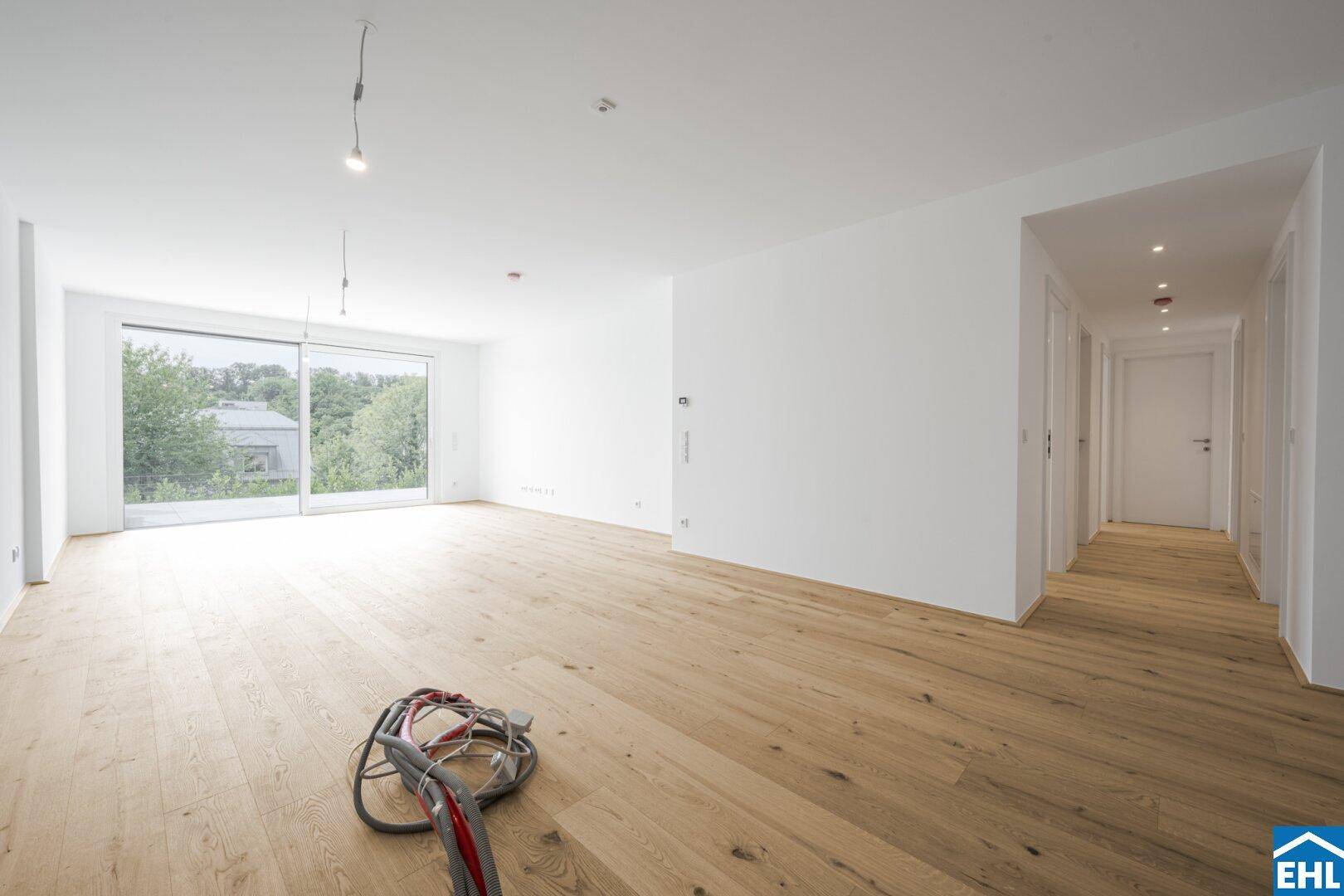 Heller, leerer Wohnraum mit Eichenparkett und großen Schiebetüren zur Terrasse.