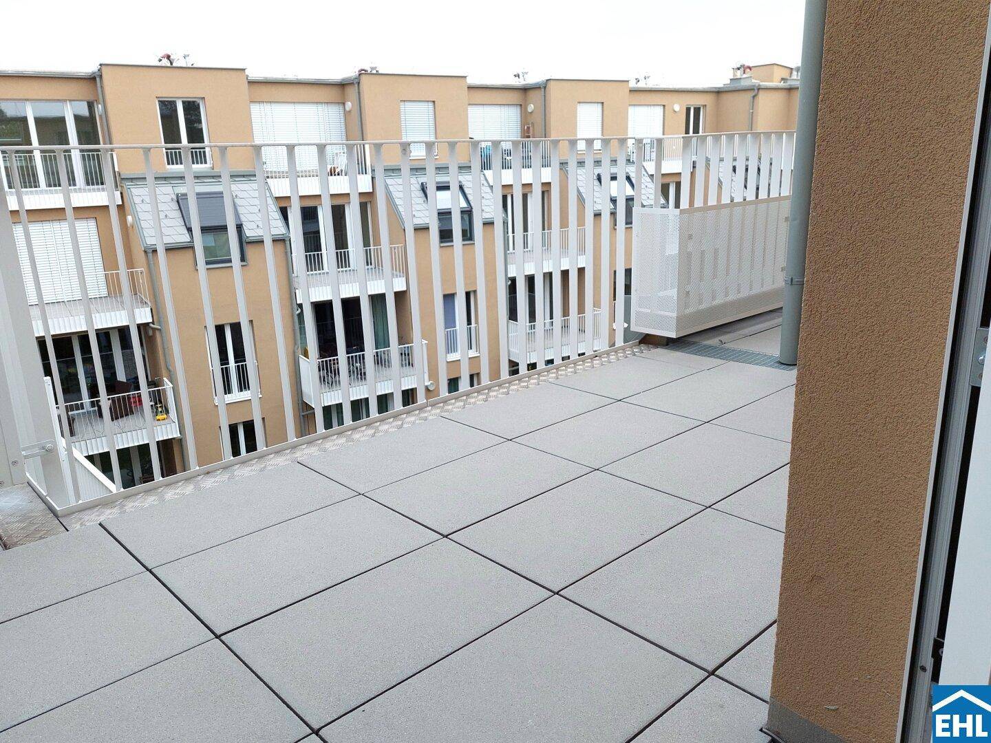 Weitläufige Dachterrasse mit moderner Balustrade und Blick auf die Nachbargebäude.