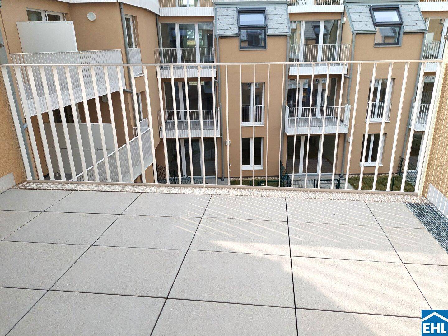 Geräumiger Balkon mit Fliesenboden und Blick auf die umliegenden Wohngebäude.