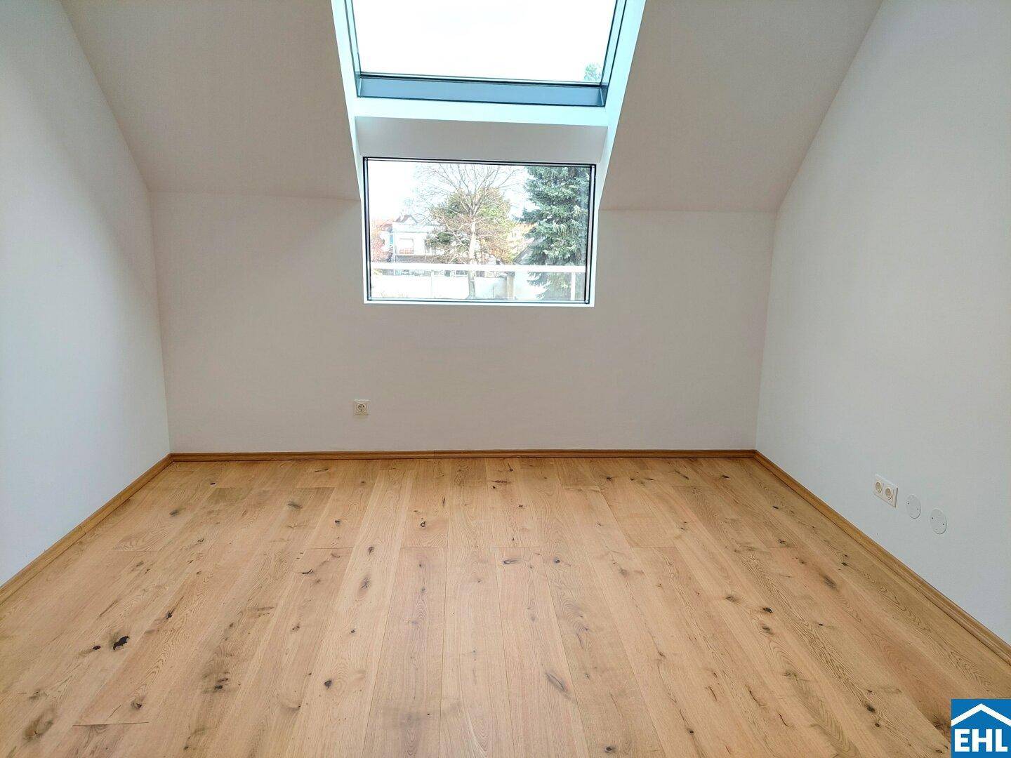 Helles Zimmer im Dachgeschoss mit Holzboden und Dachfenster, bietet Blick ins Grüne und viel Licht.