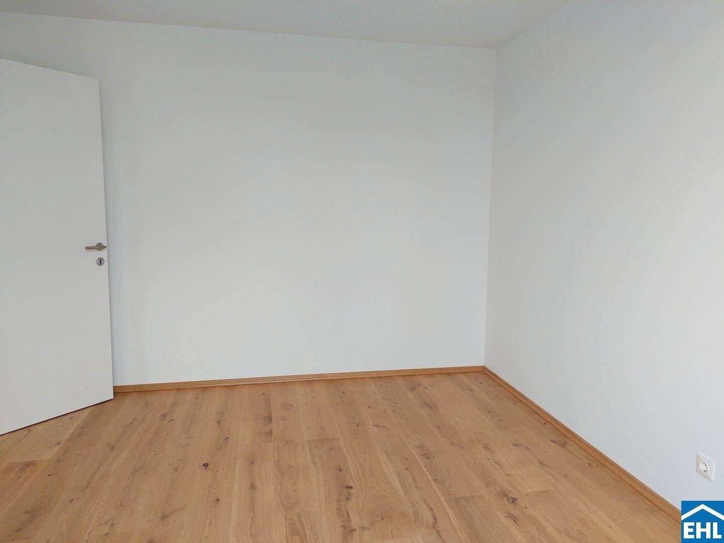 Leerer Raum mit weiß gestrichenen Wänden und hellem Holzboden, bereit zur individuellen Gestaltung.
