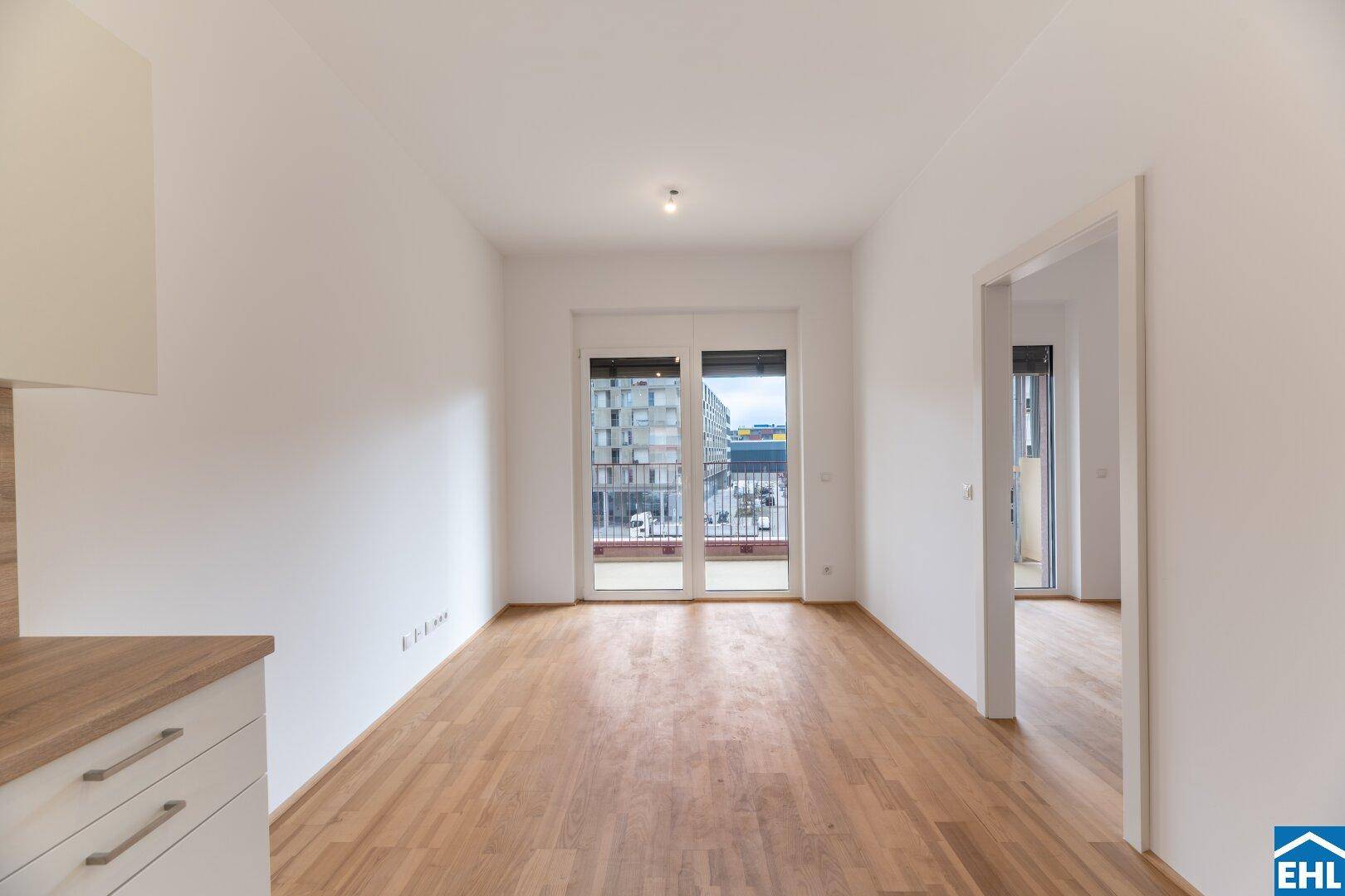 Geräumiger, heller Wohnbereich mit Parkettboden und großen Fenstern, die viel Tageslicht hereinlassen.