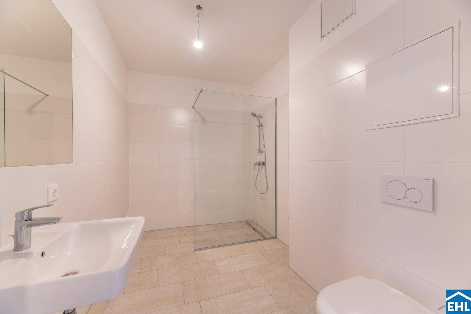 Modernes Badezimmer mit ebenerdiger Dusche und hellen Fliesen, minimalistisch und funktional gestaltet.