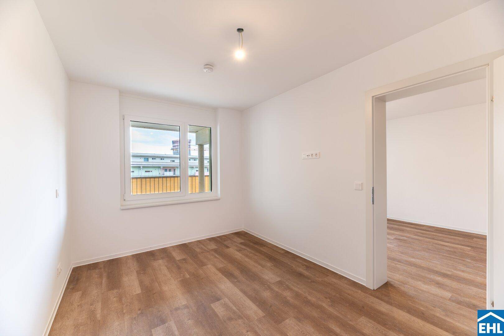 Helles Schlafzimmer mit Laminatboden und großem Fenster, bereit zur individuellen Gestaltung.