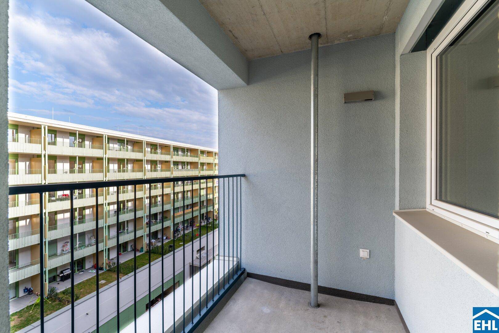 Balkon mit Metallgeländer und Blick auf die gegenüberliegenden Wohngebäude.