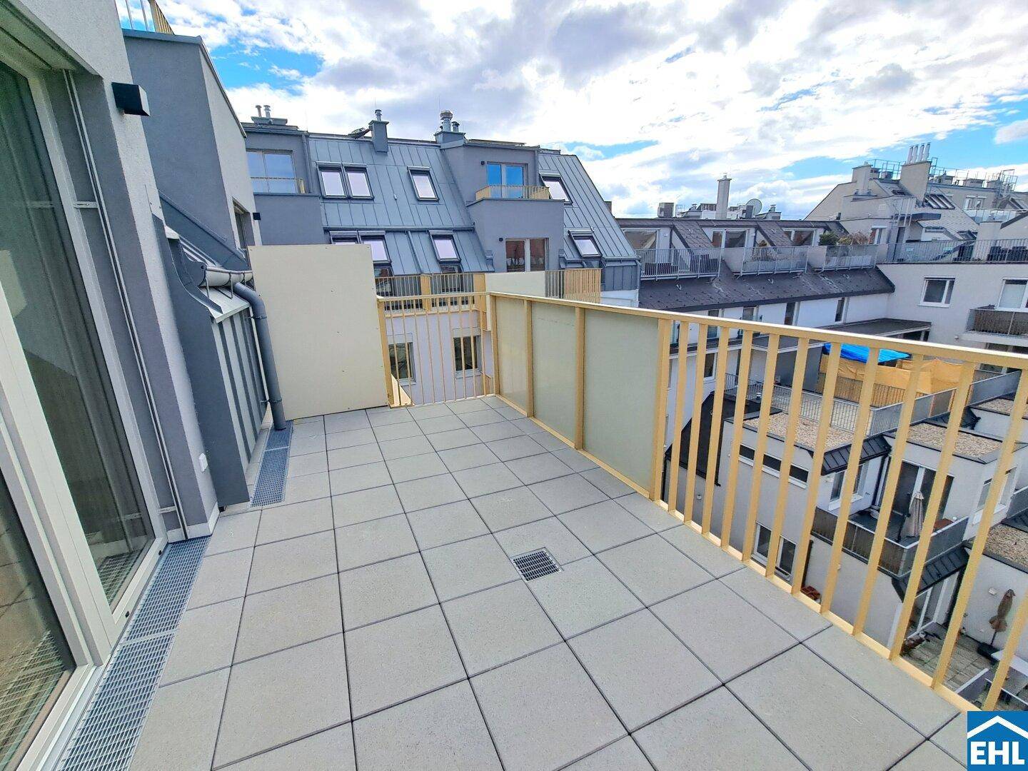 Geräumige Dachterrasse mit Fliesenboden und Blick auf die umliegenden Dächer.