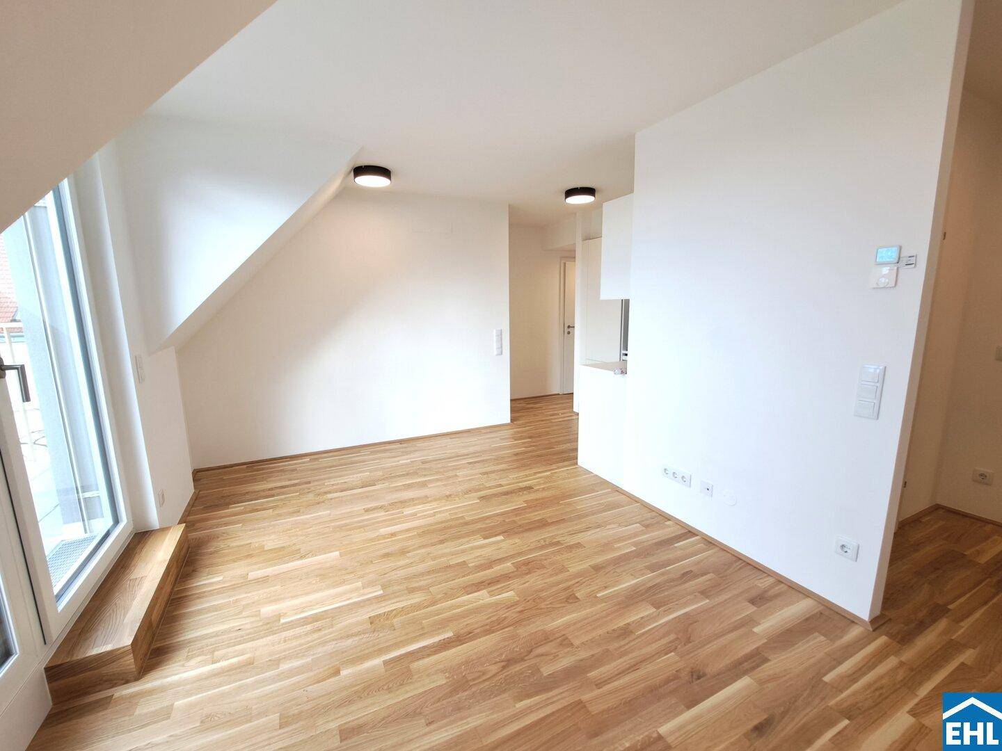 Offener Wohnbereich im Dachgeschoss mit Parkettboden und viel Tageslicht.