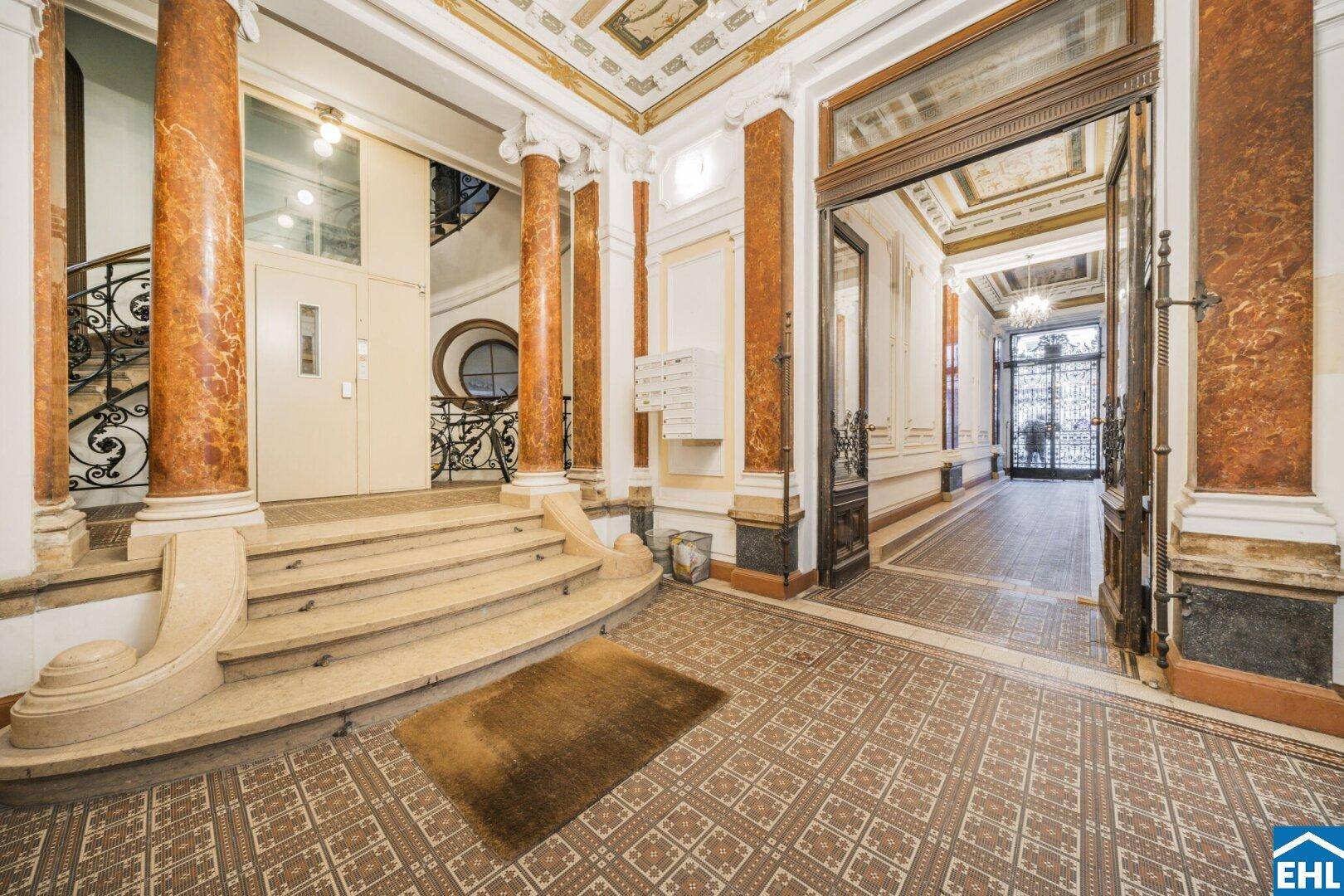 Eindrucksvoller Eingangsbereich mit kunstvollen Bodenfliesen, Marmorsäulen und Zugang zum Treppenhaus.