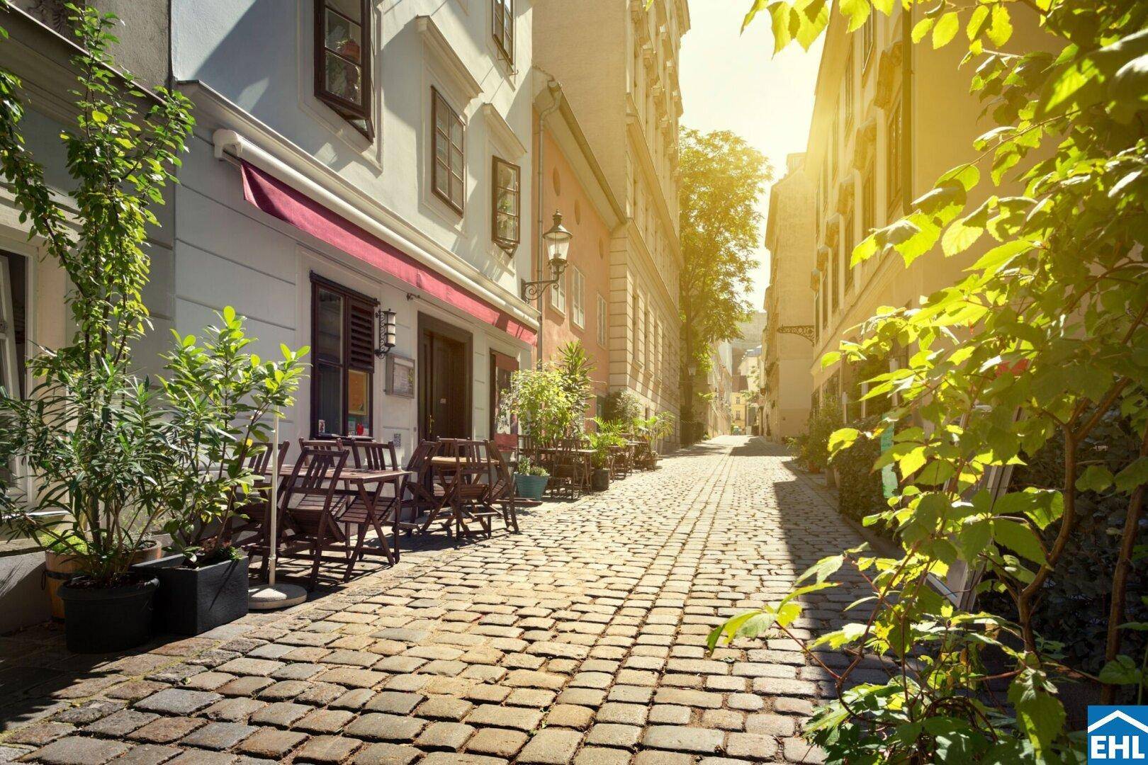 Sonnige Kopfsteinpflastergasse mit charmanten Cafés und Restaurants im historischen Stadtzentrum.