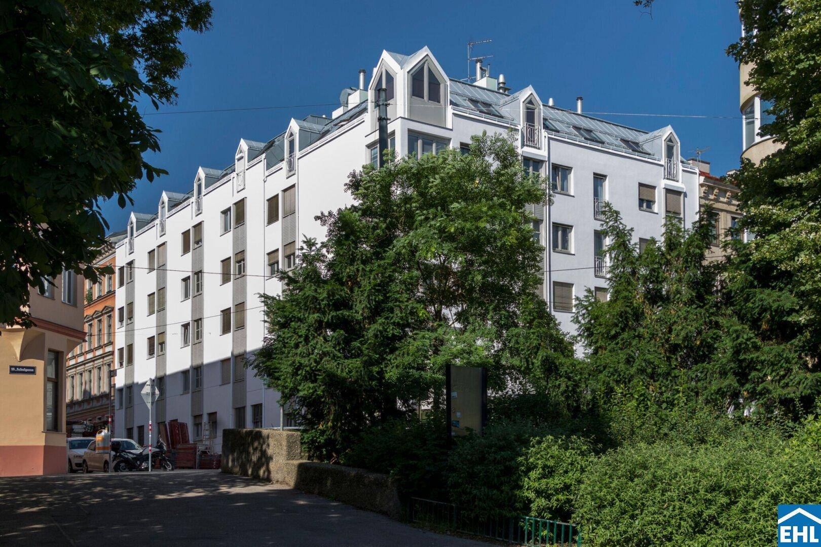 Ansicht des modernen Gebäudes mit weißer Fassade und grüner Umgebung unter blauem Himmel.