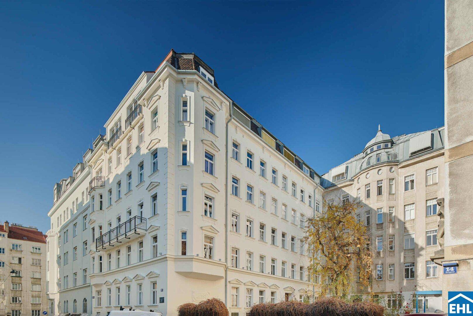 Elegantes weißes Gebäude mit klassischer Fassade und vielen Fenstern unter klarem Himmel.