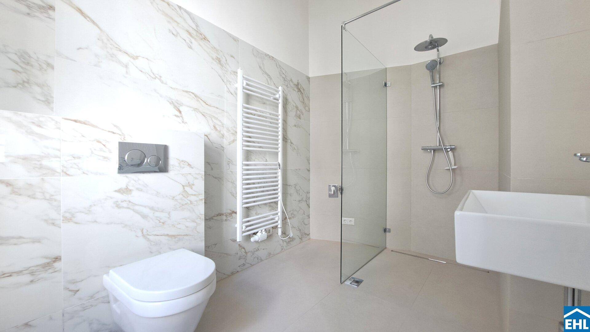Modernes Badezimmer mit Marmorfliesen, ebenerdiger Dusche, Wand-WC und beheiztem Handtuchhalter.