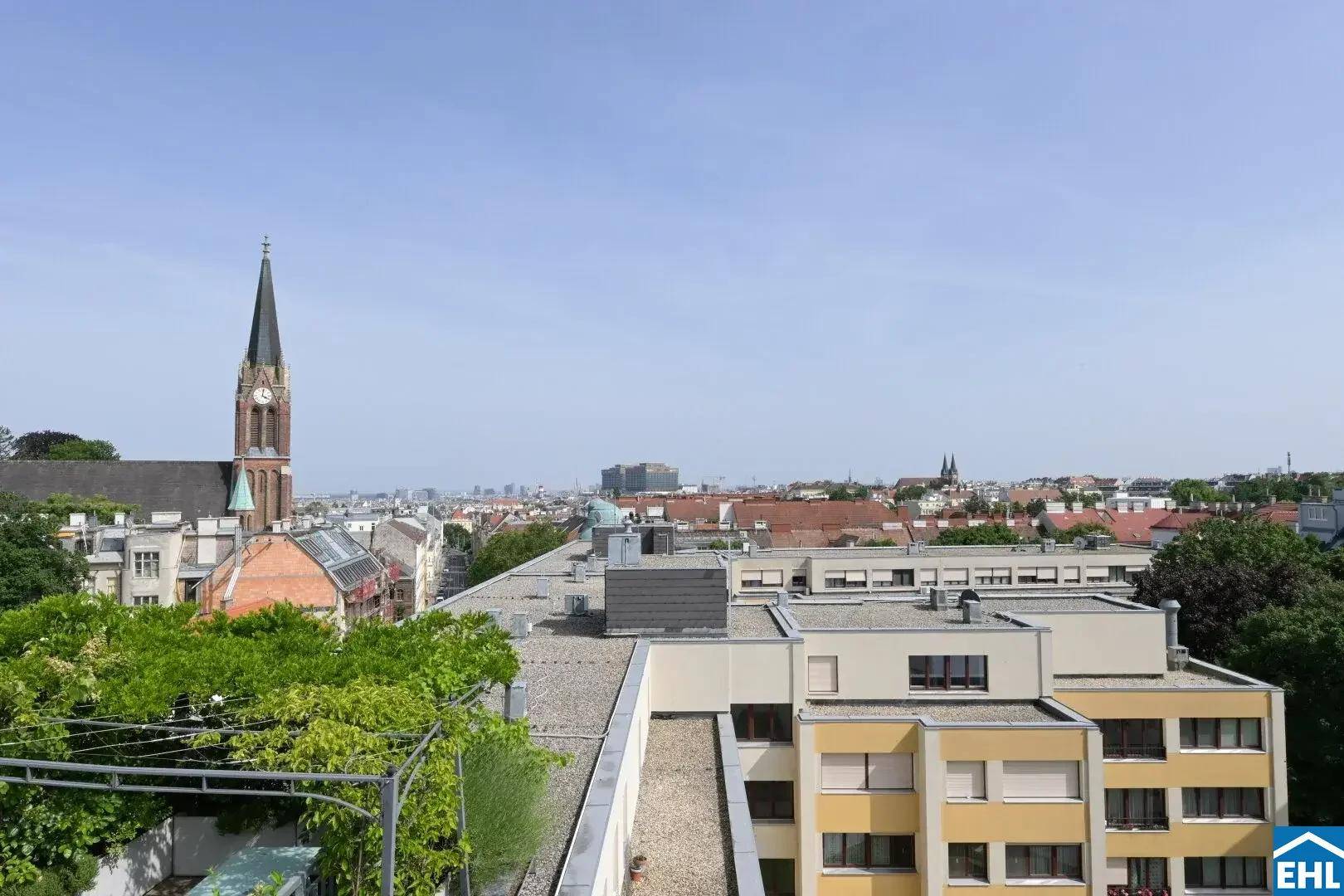 Panoramablick von der Dachterrasse auf die städtische Umgebung mit verschiedenen Gebäuden und einer Kirche.