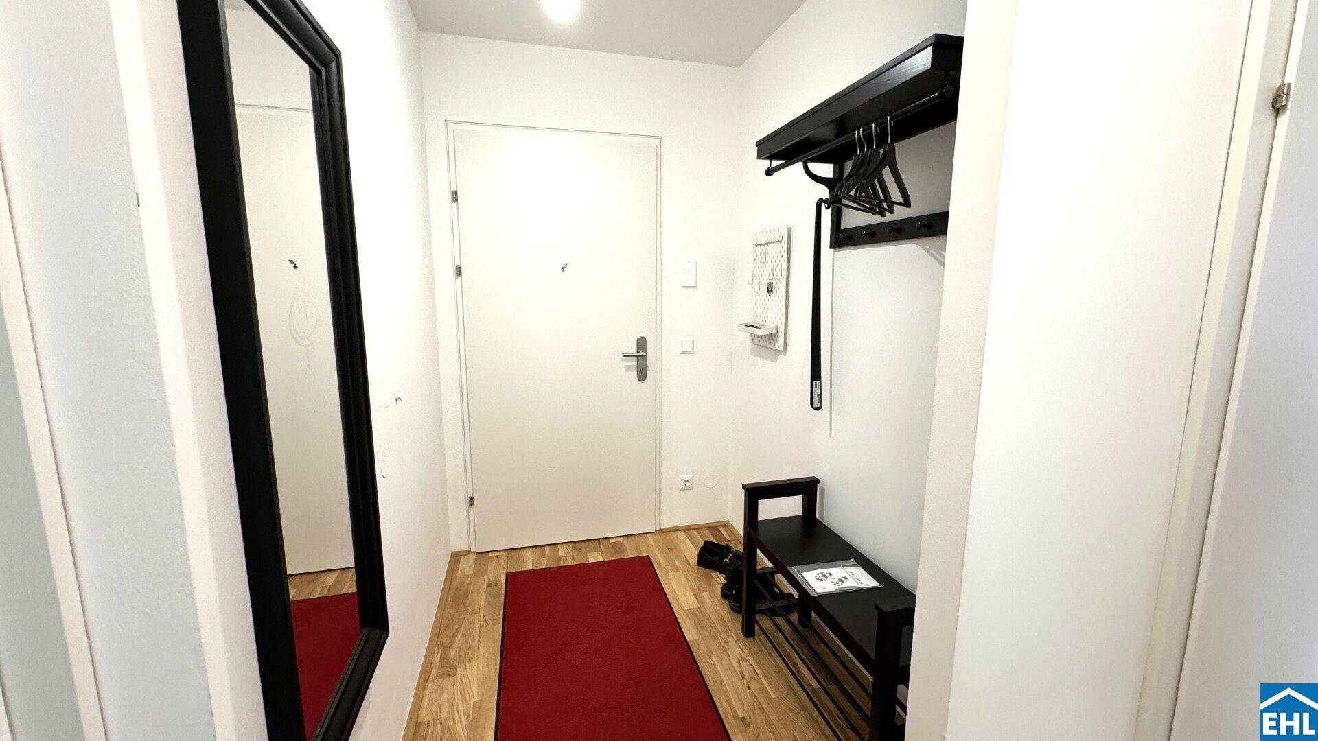 Eingangsbereich mit Garderobe, Spiegel und Holzboden.