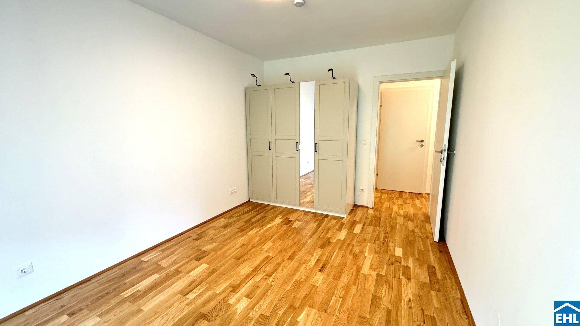 Geräumiges Schlafzimmer mit Holzboden und hellem Kleiderschrank.