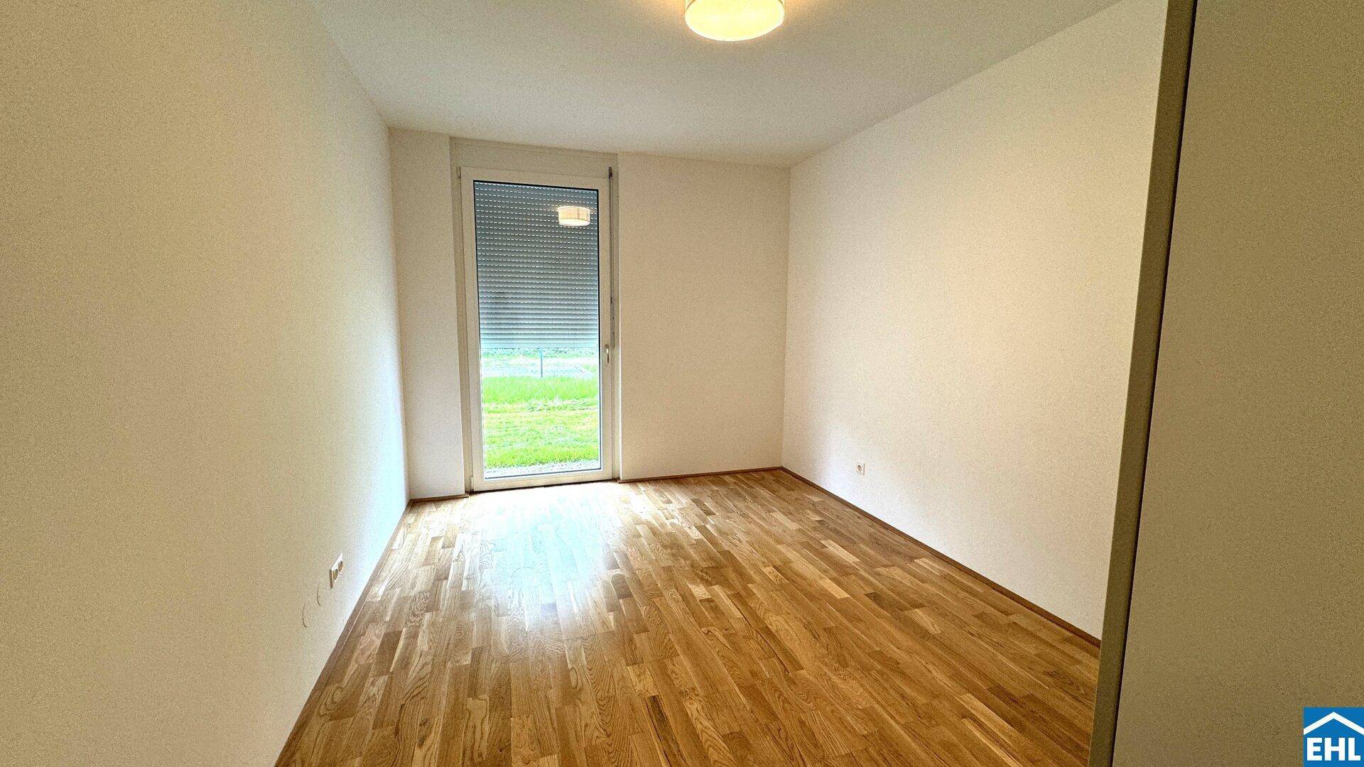Helles Schlafzimmer mit Holzboden und Zugang zum Außenbereich.