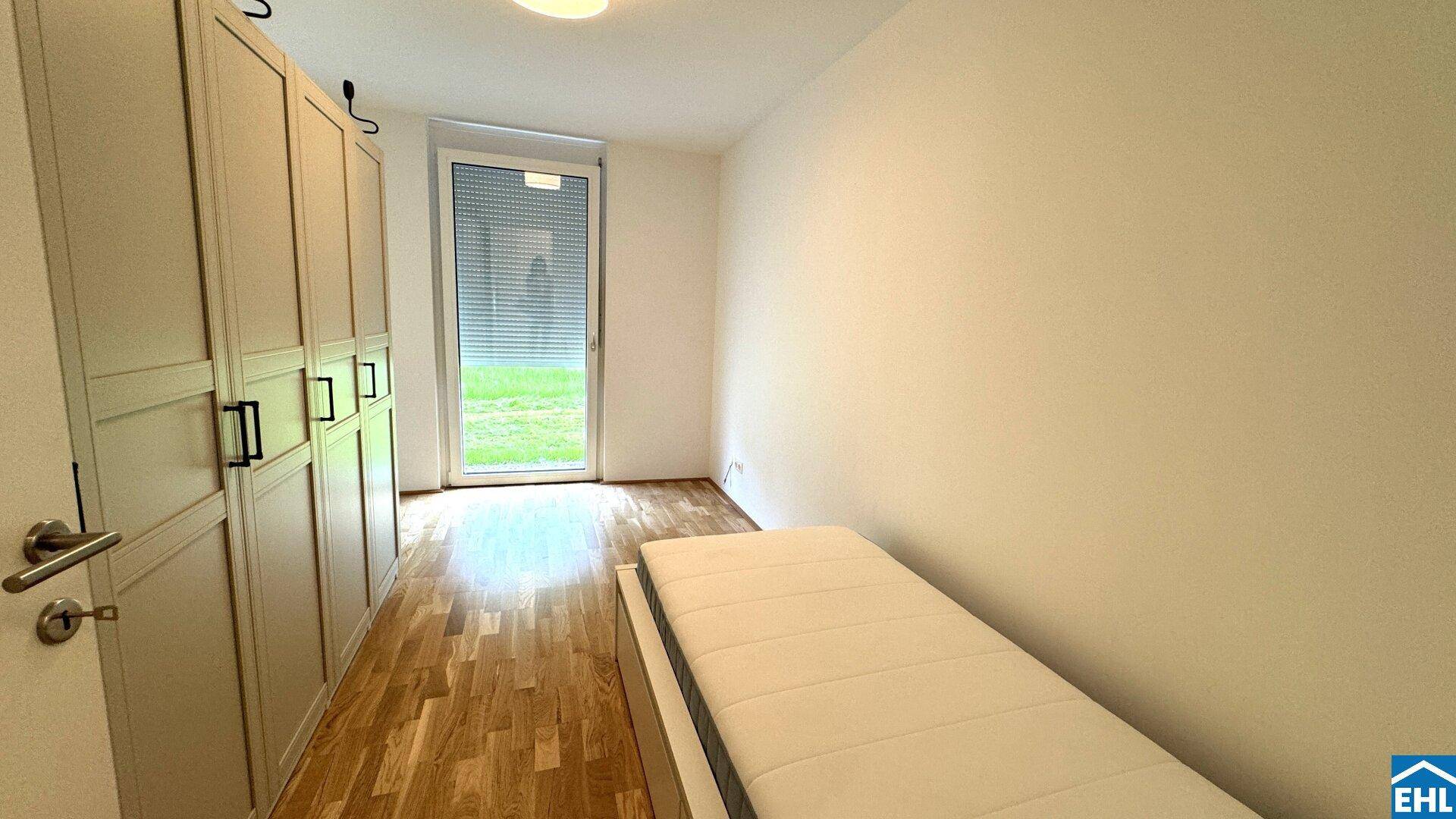 Schlafzimmer mit Holzboden, Kleiderschrank und Zugang zum Garten.