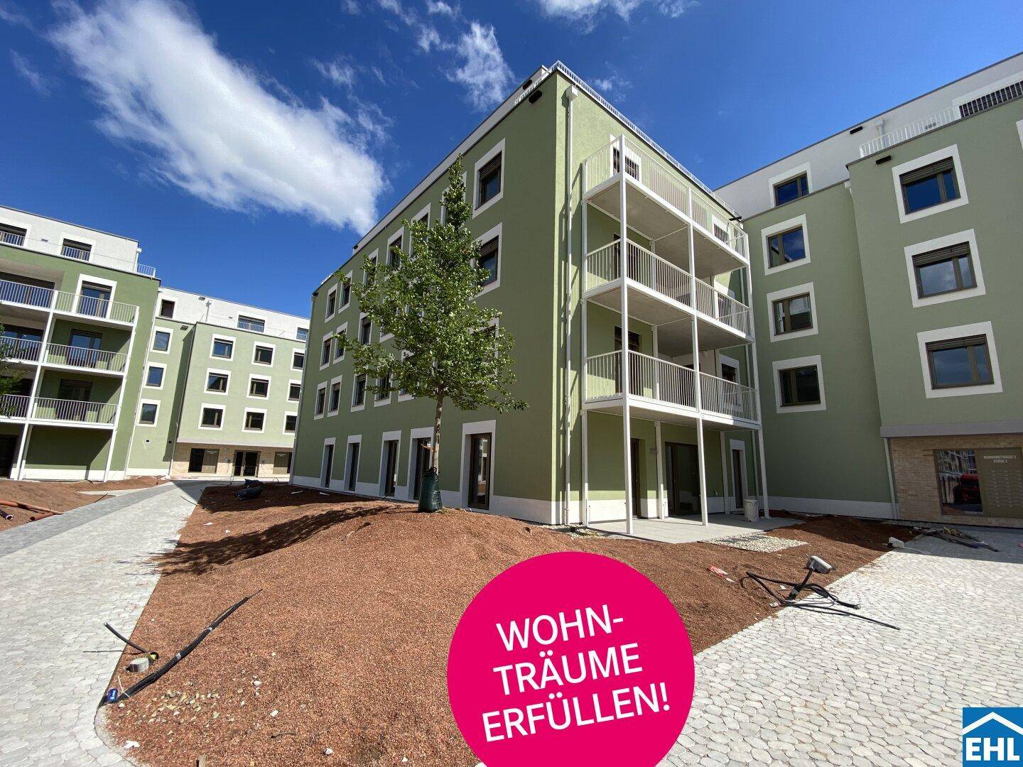 Moderne Wohnanlage mit grüner Fassade und Balkonen, umgeben von Baustellenbereich.