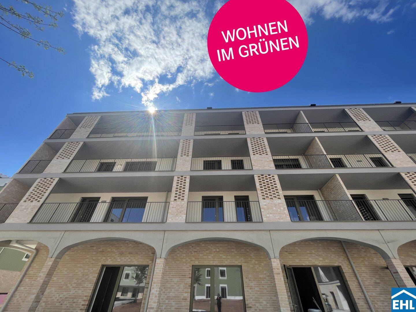Modernes Mehrfamilienhaus mit Balkonen und Ziegelfassade unter blauem Himmel.