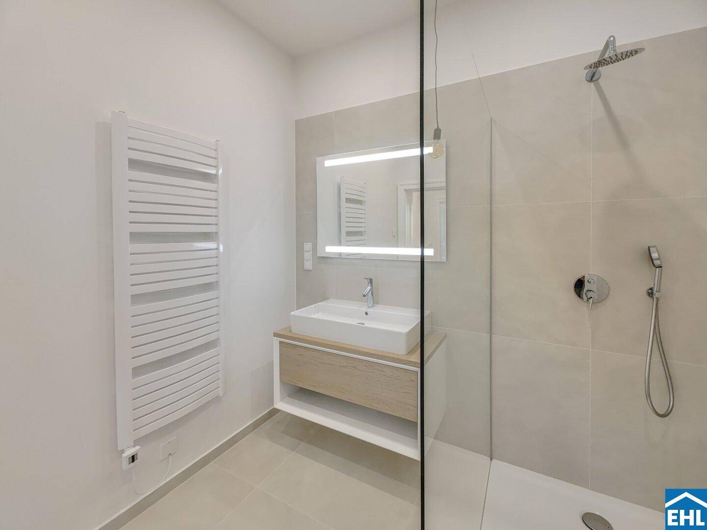 Modernes Badezimmer mit ebenerdiger Dusche, Einzelwaschbecken und beheiztem Handtuchhalter.