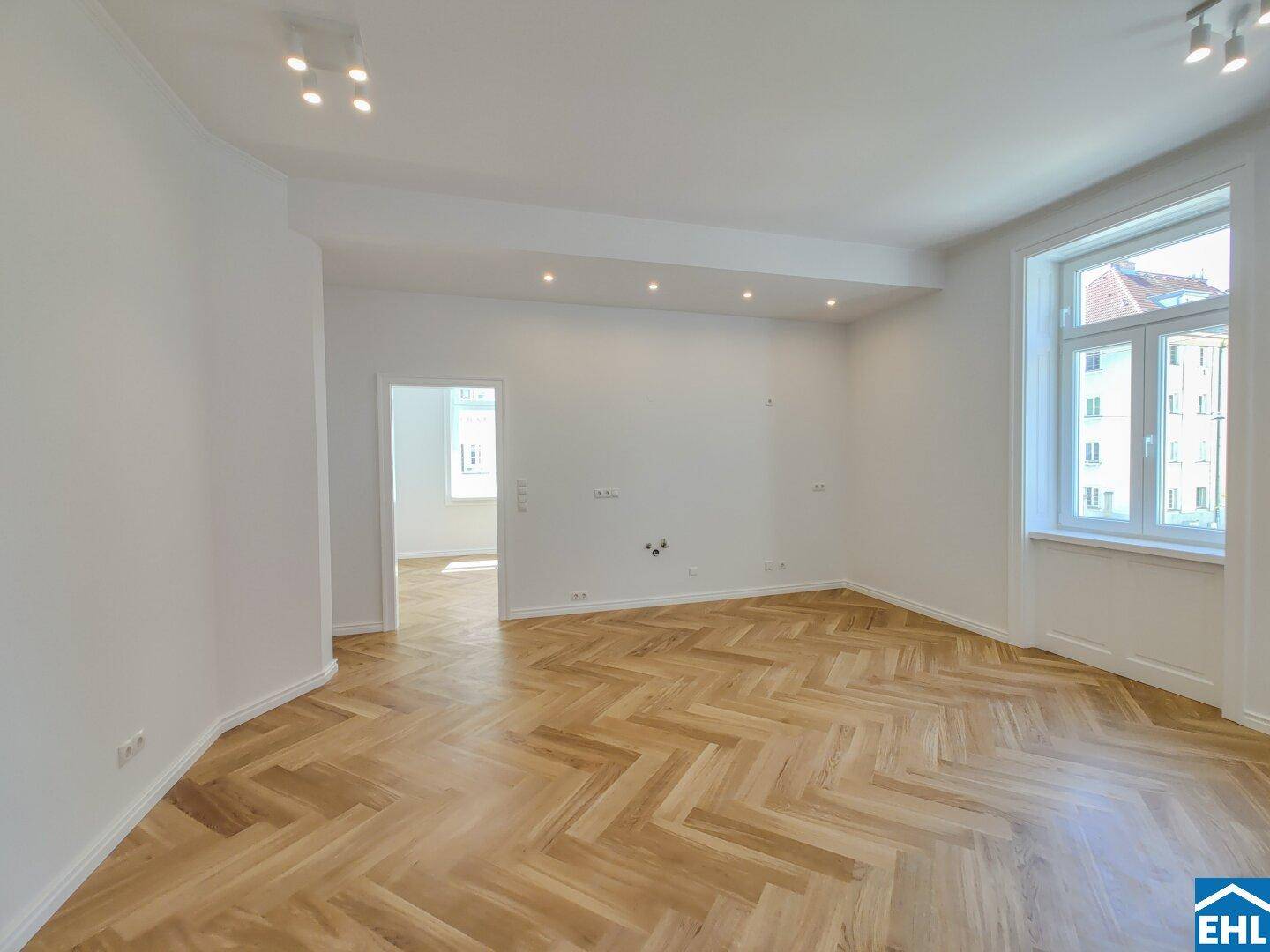 Heller Wohnbereich mit Fischgrätparkett und Einbaustrahlern in der Decke für angenehme Beleuchtung.