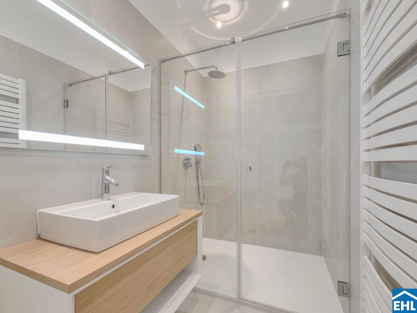 Modernes Badezimmer mit begehbarer Dusche, Einzelwaschbecken und beheiztem Handtuchhalter.