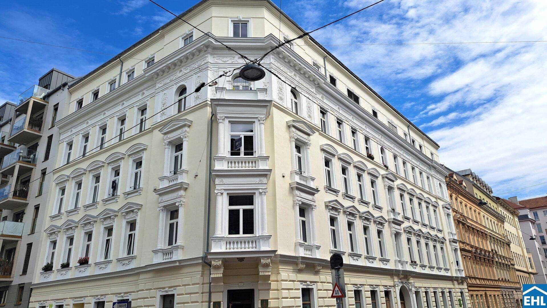 Elegantes Eckgebäude mit klassischer Architektur und vielen Fenstern in einer städtischen Umgebung.