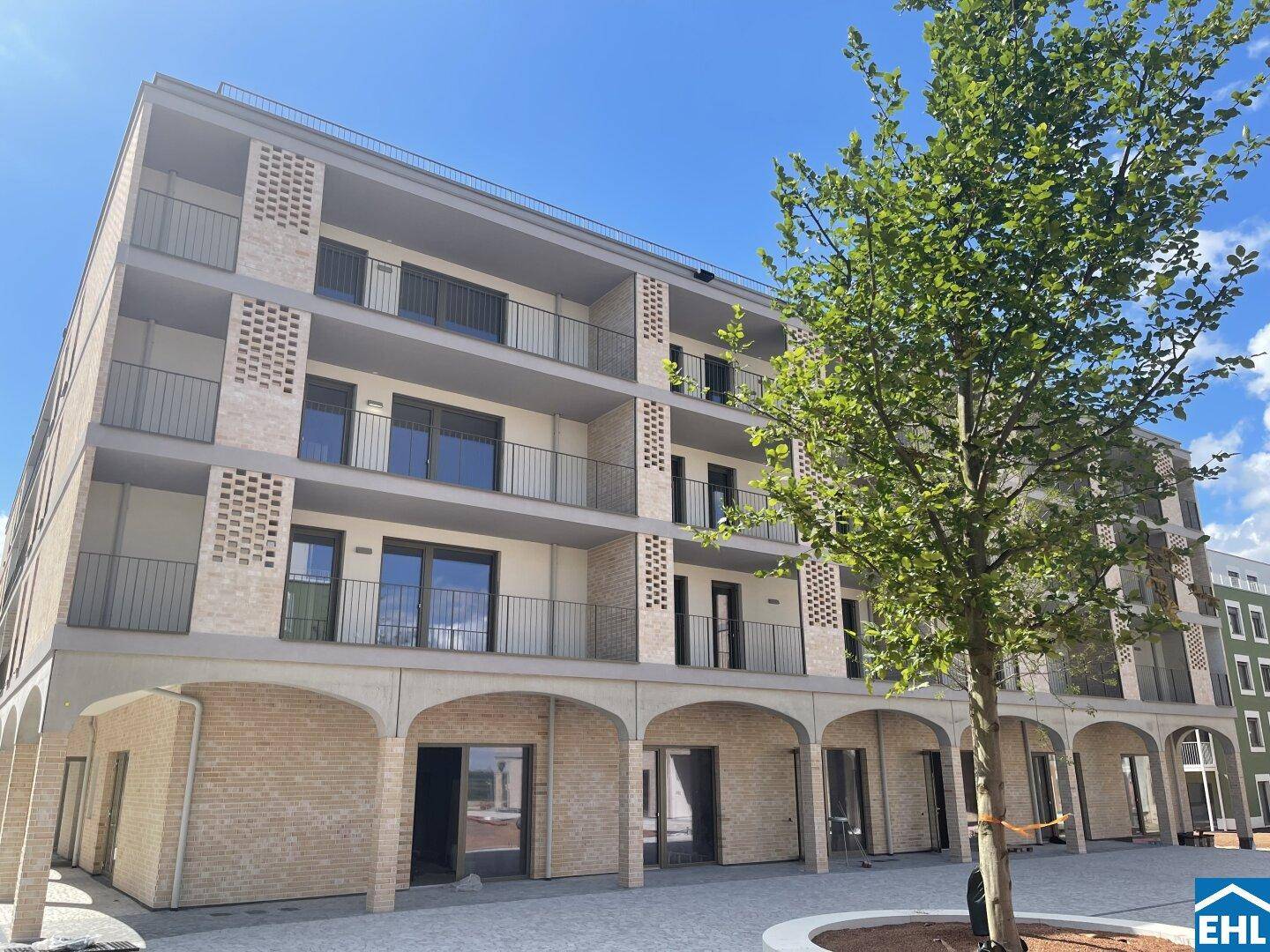 Moderne Fassade des Neubaus mit Balkonen und Arkaden im Erdgeschoss.