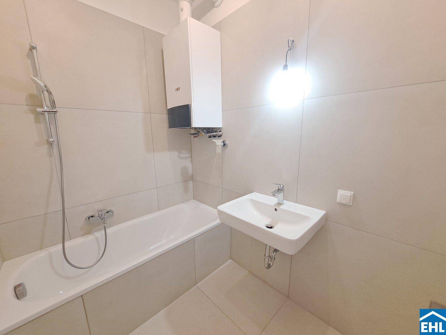 Modernes Badezimmer mit Badewanne, Waschbecken und Gastherme an der Wand.