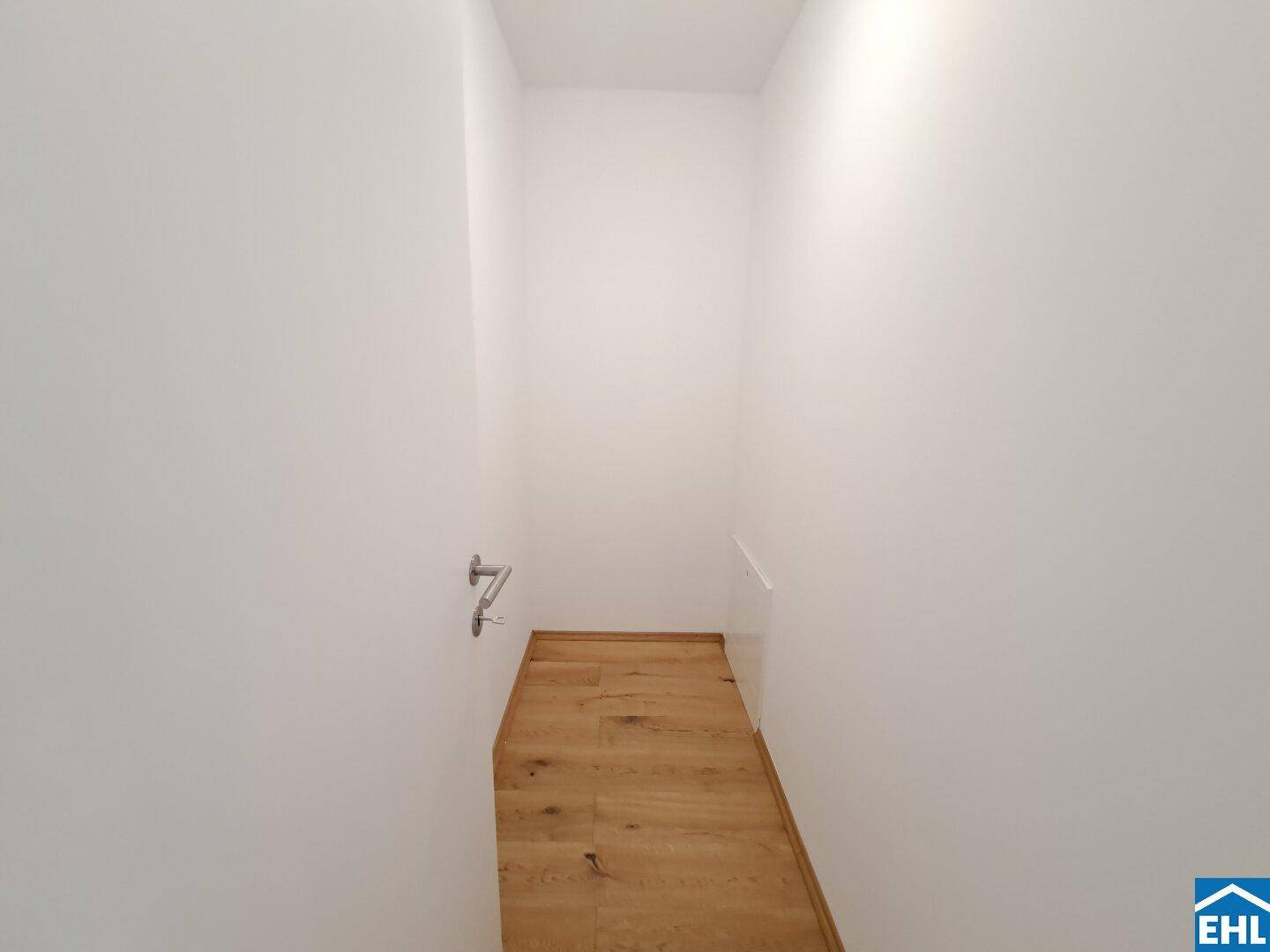 Praktischer begehbarer Kleiderschrank mit Holzboden und viel Stauraum.