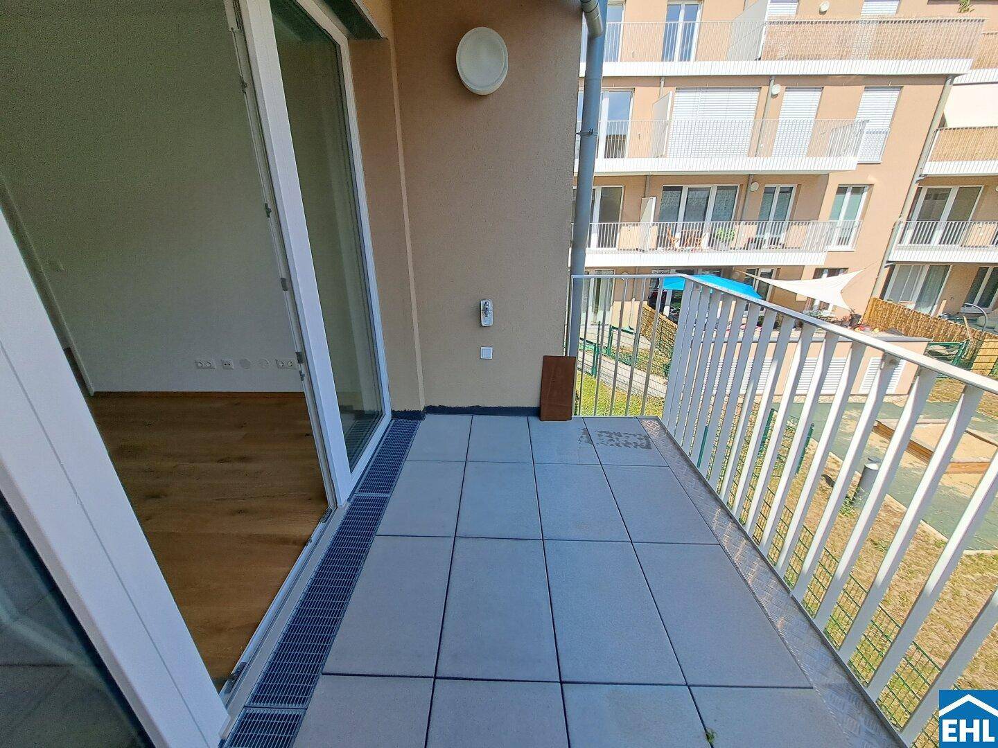 Balkon mit Fliesenboden und Blick auf die umliegenden Gebäude, ideal für entspannte Stunden im Freien.