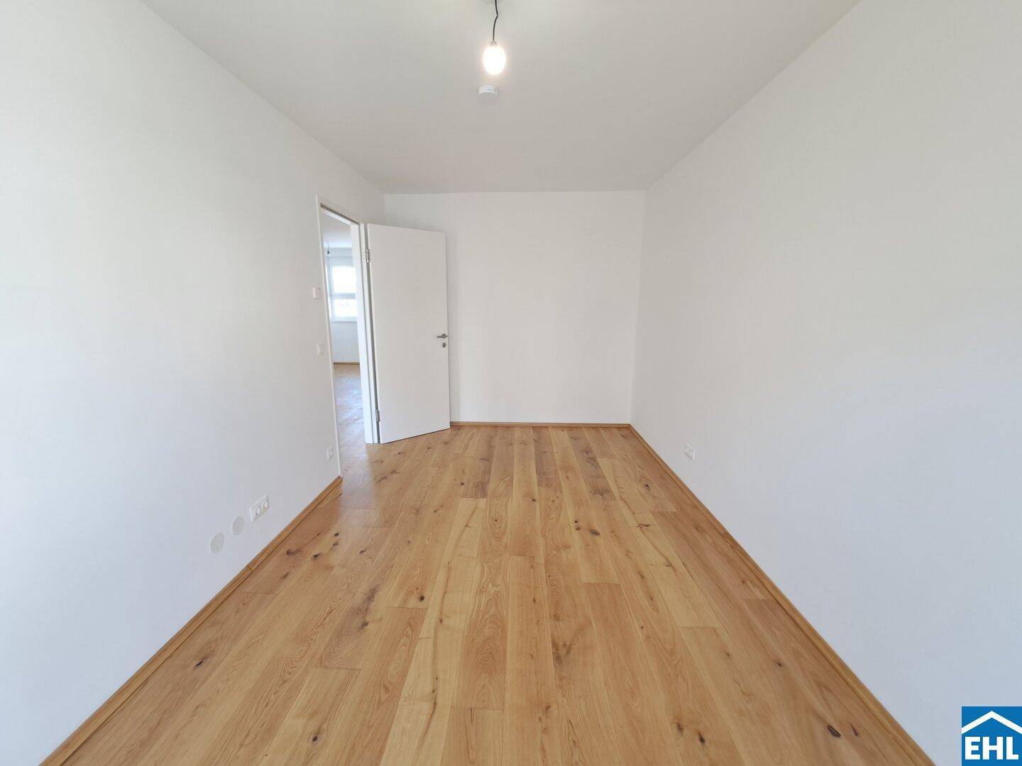 Geräumiges Schlafzimmer mit hellem Parkettboden und weißen Wänden, bereit zur individuellen Einrichtung.