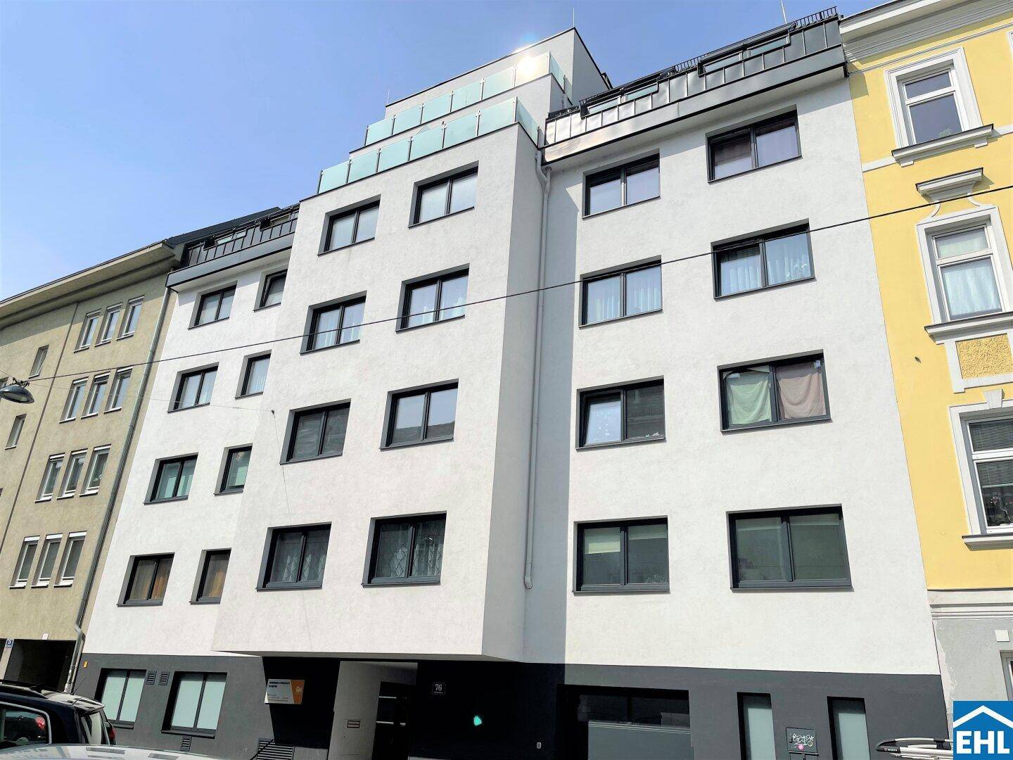 Moderne Wohnhausfassade mit vielen Fenstern und Balkonen in urbaner Umgebung.
