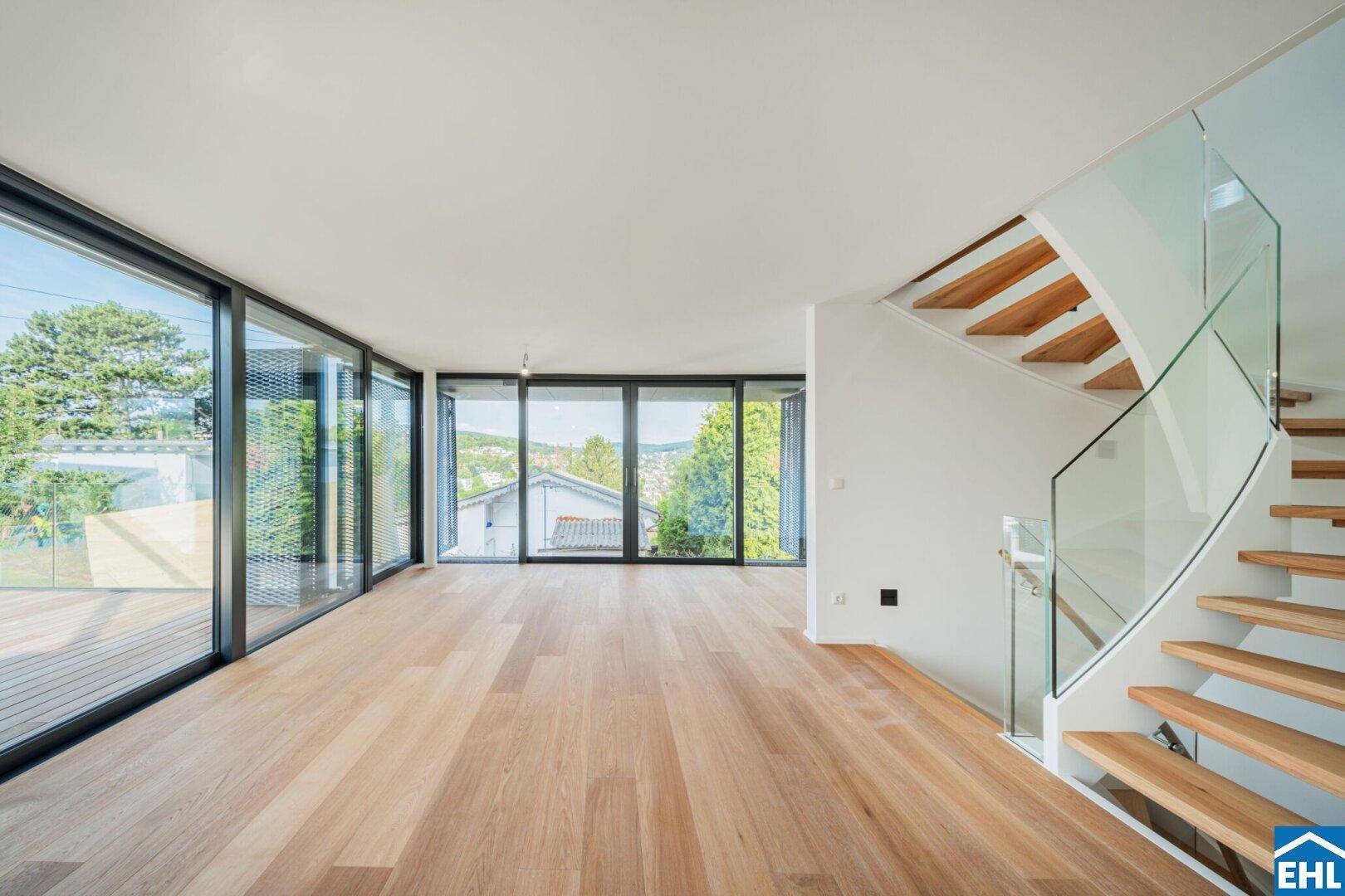 Heller, offener Wohnbereich mit Holzparkett, großen Fensterfronten und moderner Treppe.