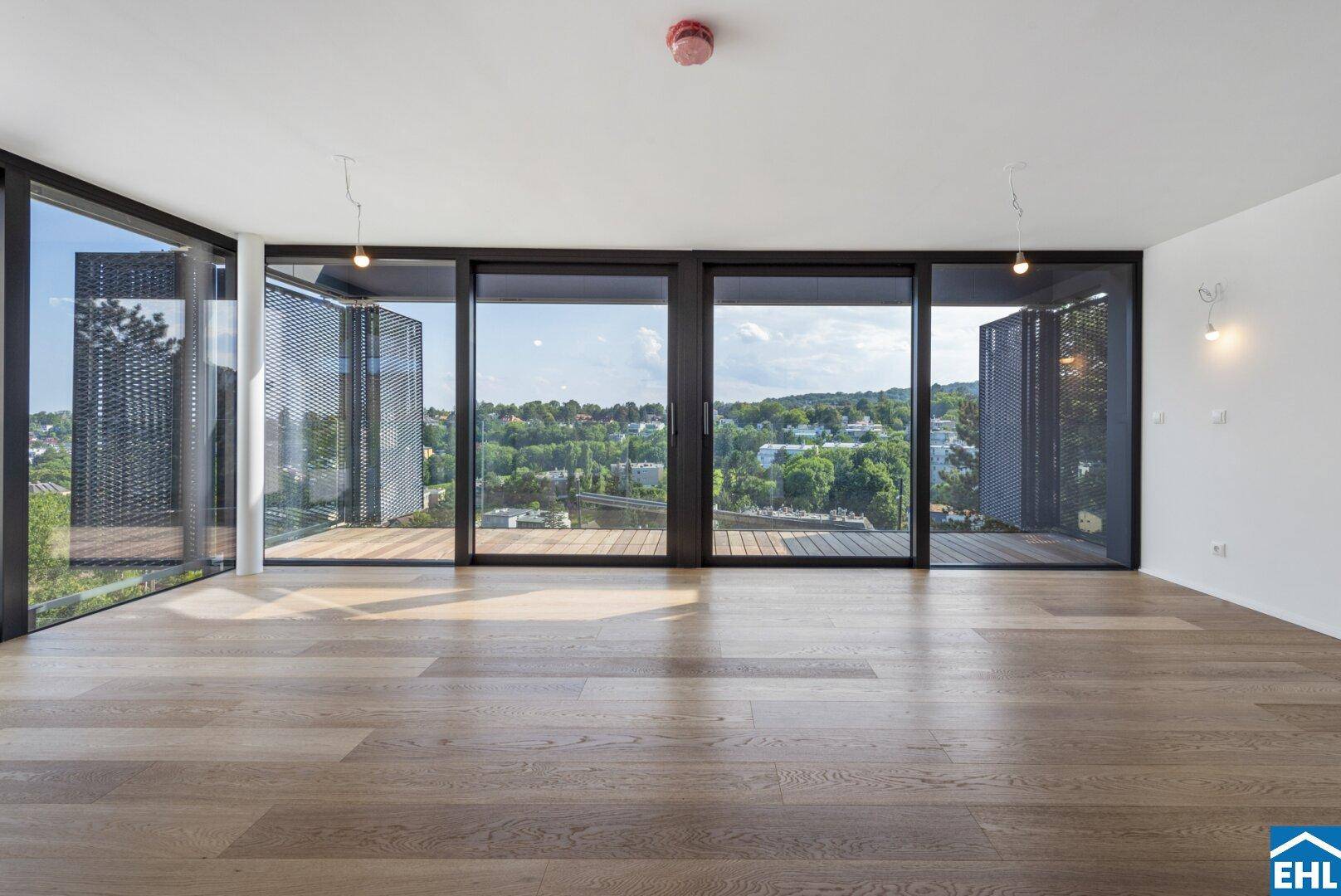 Heller Wohnraum mit Holzboden, großen Schiebefenstern und weitem Blick ins Grüne.