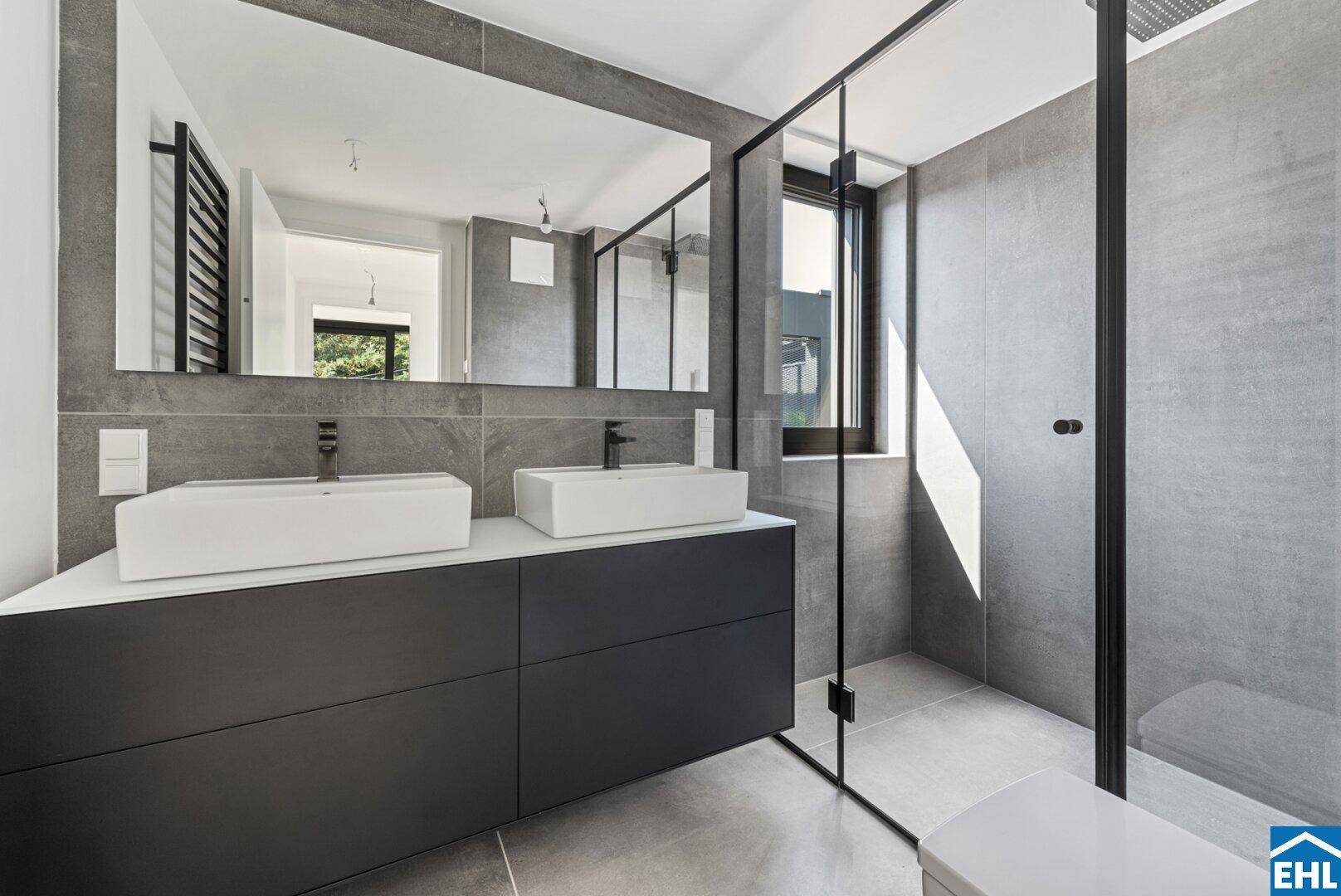 Elegantes Badezimmer mit Doppelwaschbecken, großer Dusche und modernen grauen Fliesen.