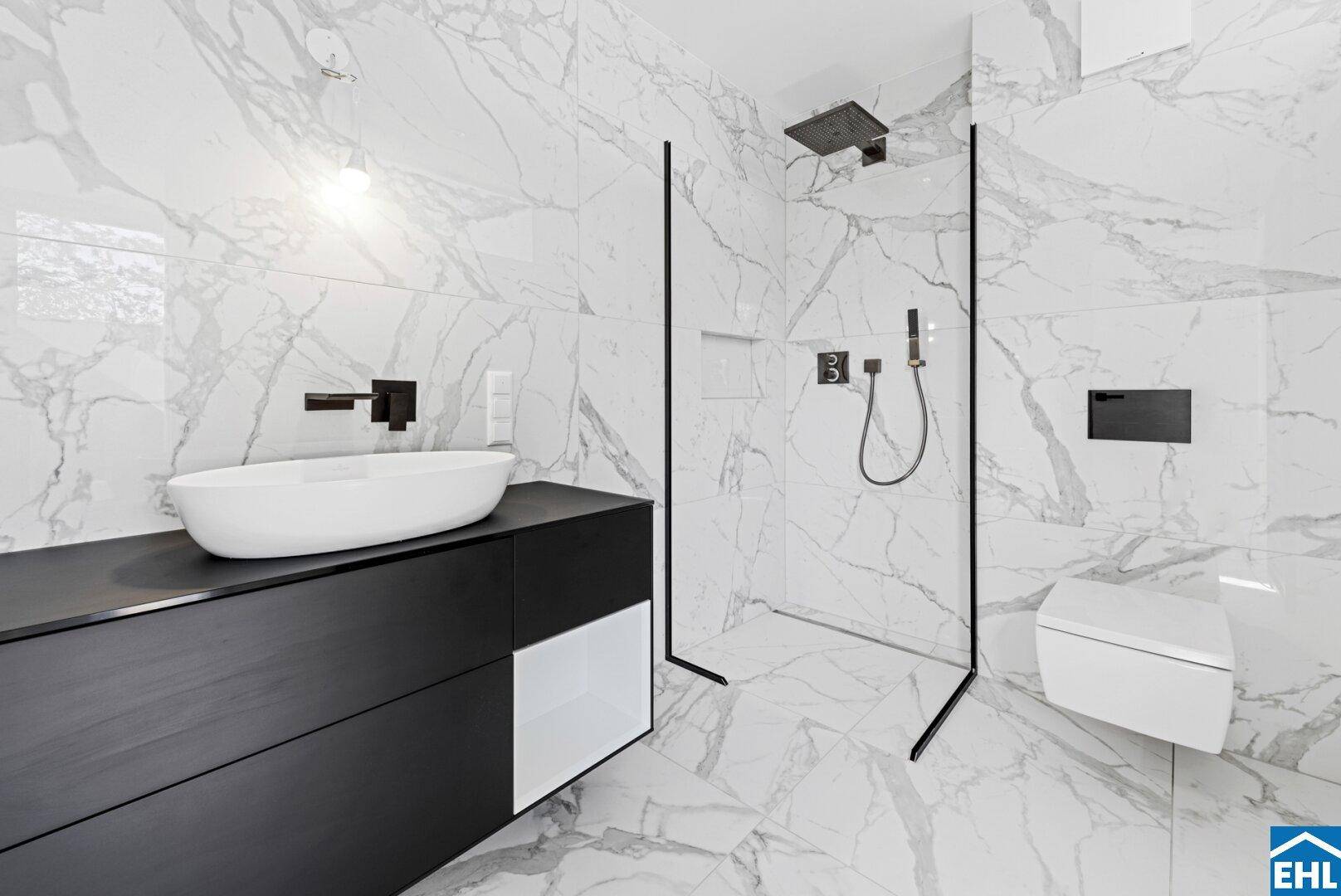 Luxuriöses Badezimmer mit Marmorfliesen, modernem Waschbecken und wandhängendem WC.