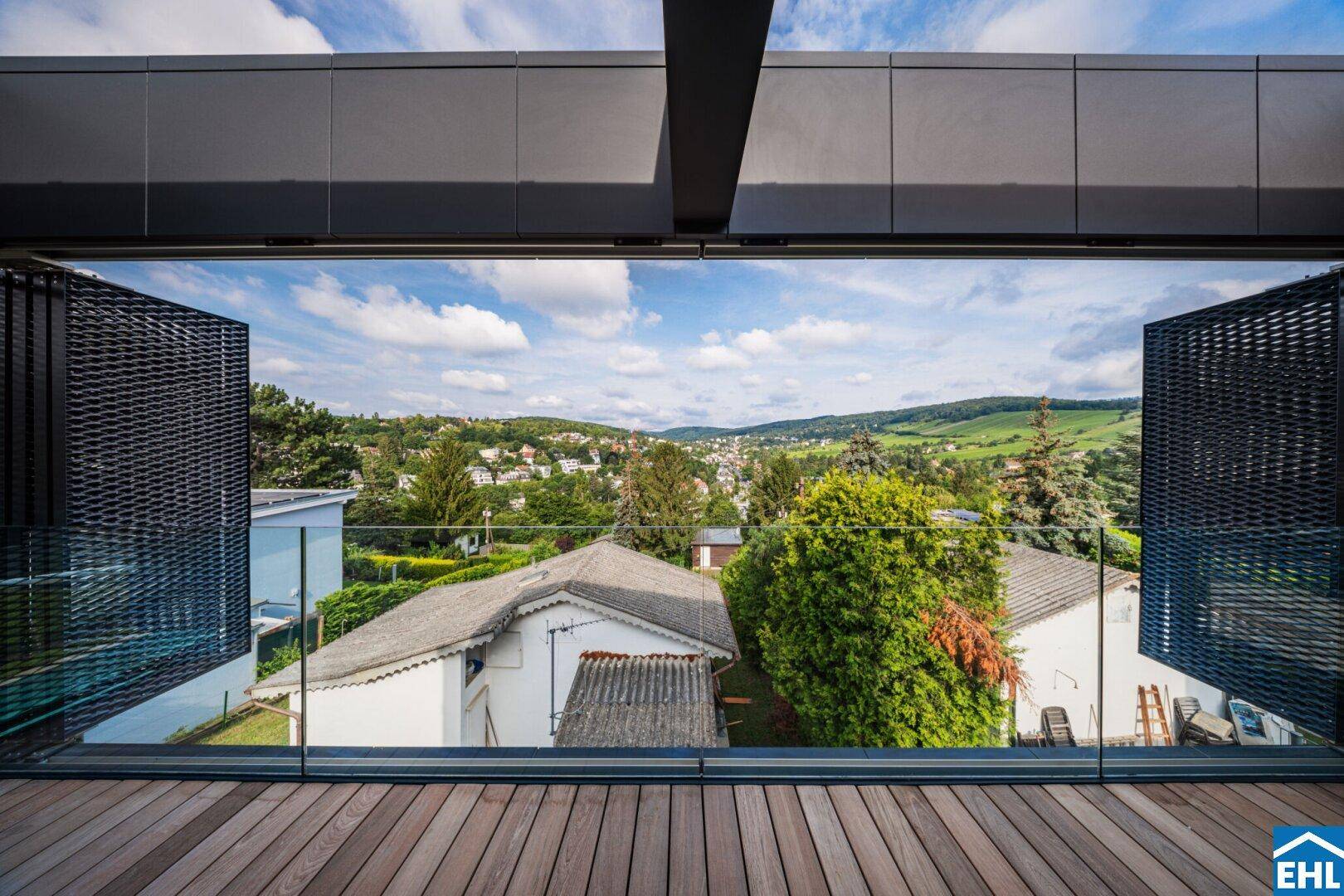 Weitläufiger Ausblick von der Terrasse auf die grüne Hügellandschaft und die umliegenden Häuser.