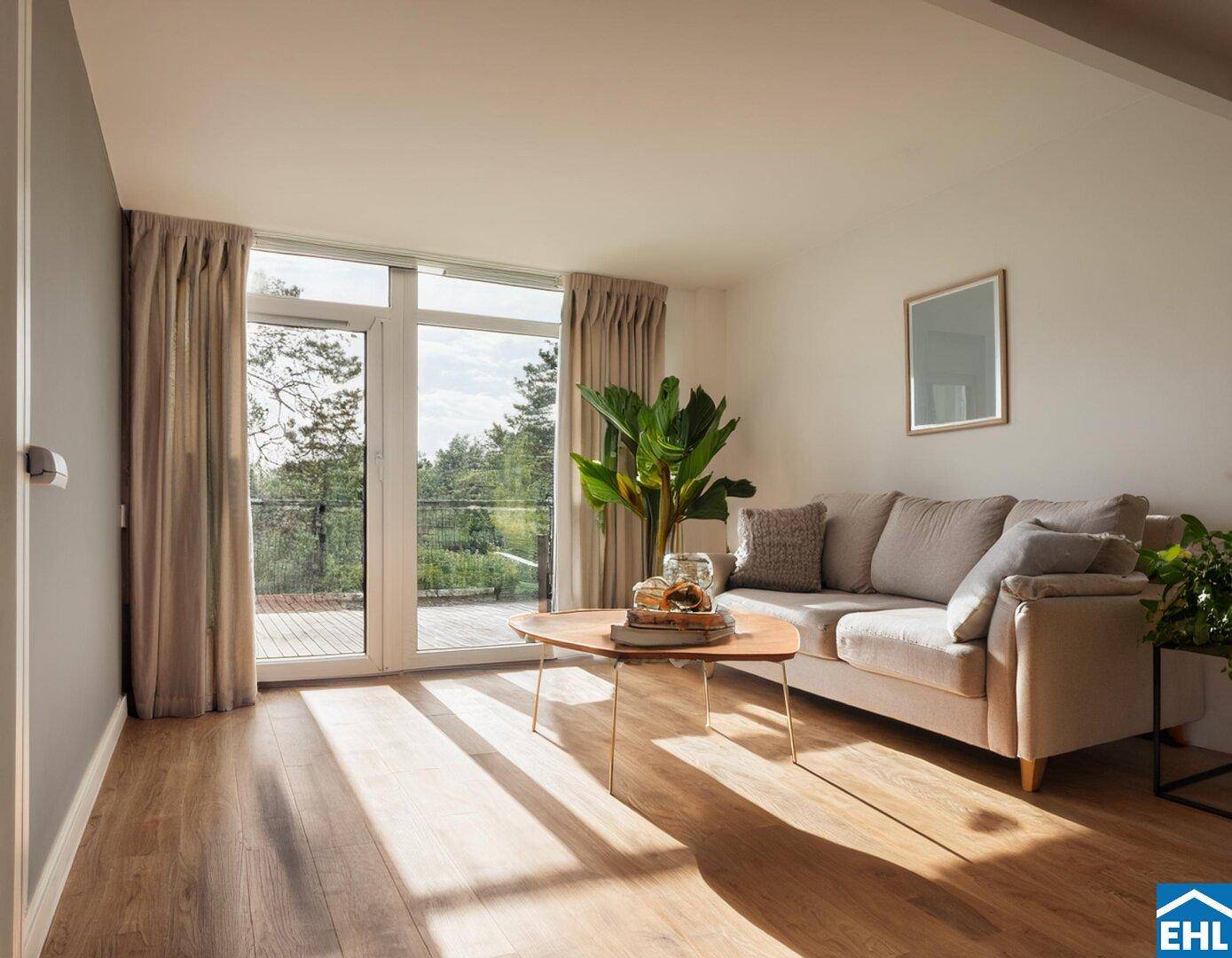 Gemütliches Wohnzimmer mit Holzboden, Sofa und Zugang zu einem Außenbereich mit Grünblick.