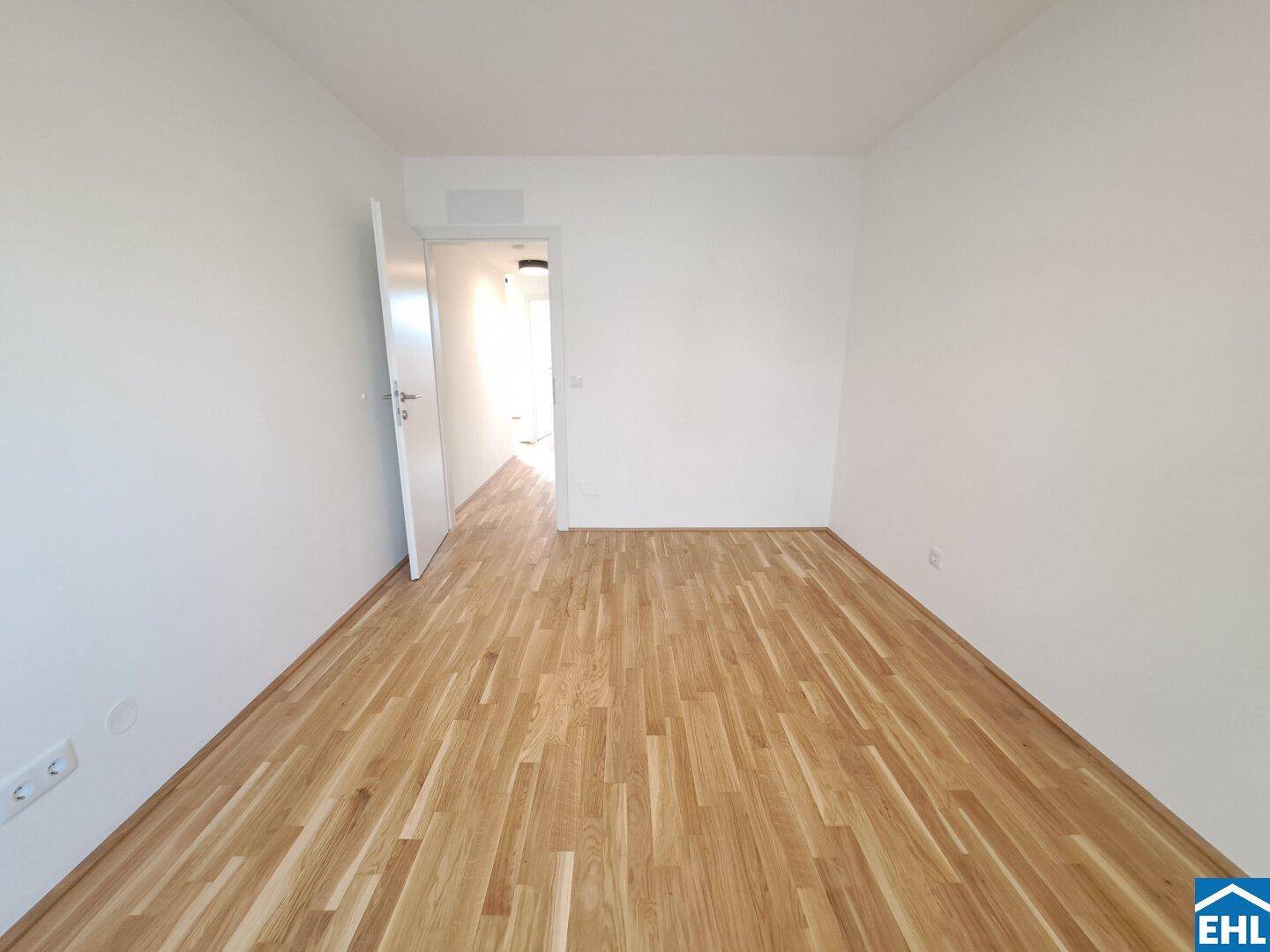 Helles Zimmer mit Parkettboden und weiß gestrichenen Wänden, ideal als Schlaf- oder Arbeitszimmer.