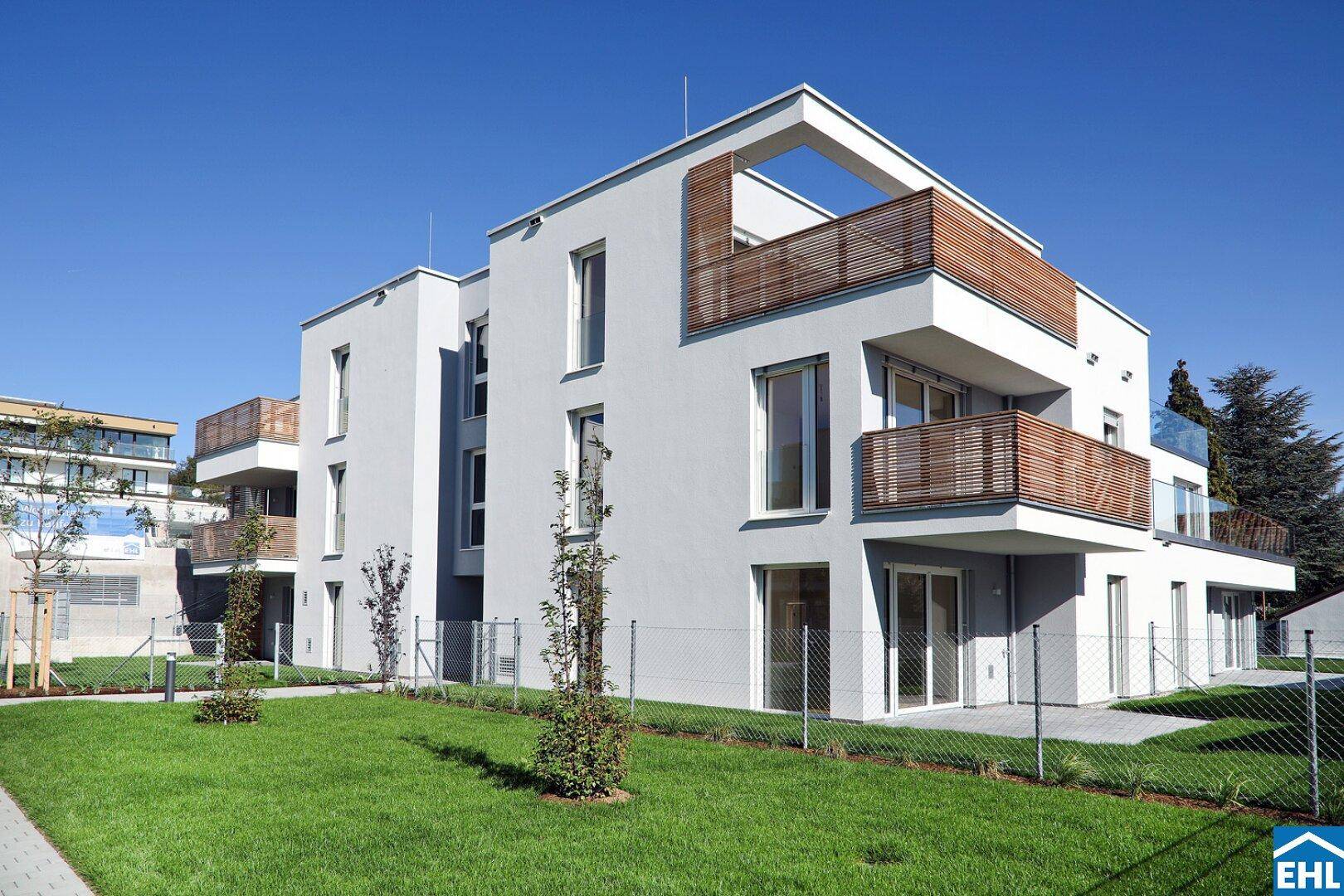 Neubau-Wohngebäude mit moderner Architektur, umgeben von einer weitläufigen Rasenfläche.