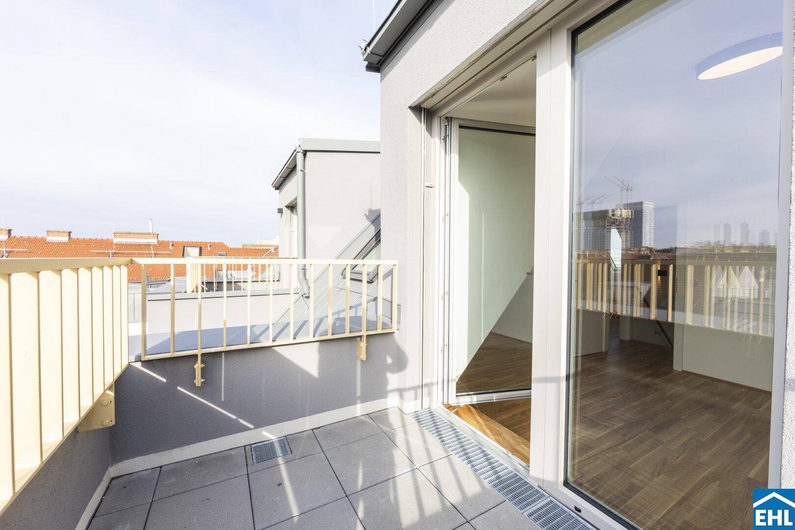 Heller Balkon mit Fliesenboden und Blick über die Dächer der umliegenden Stadtgebäude.