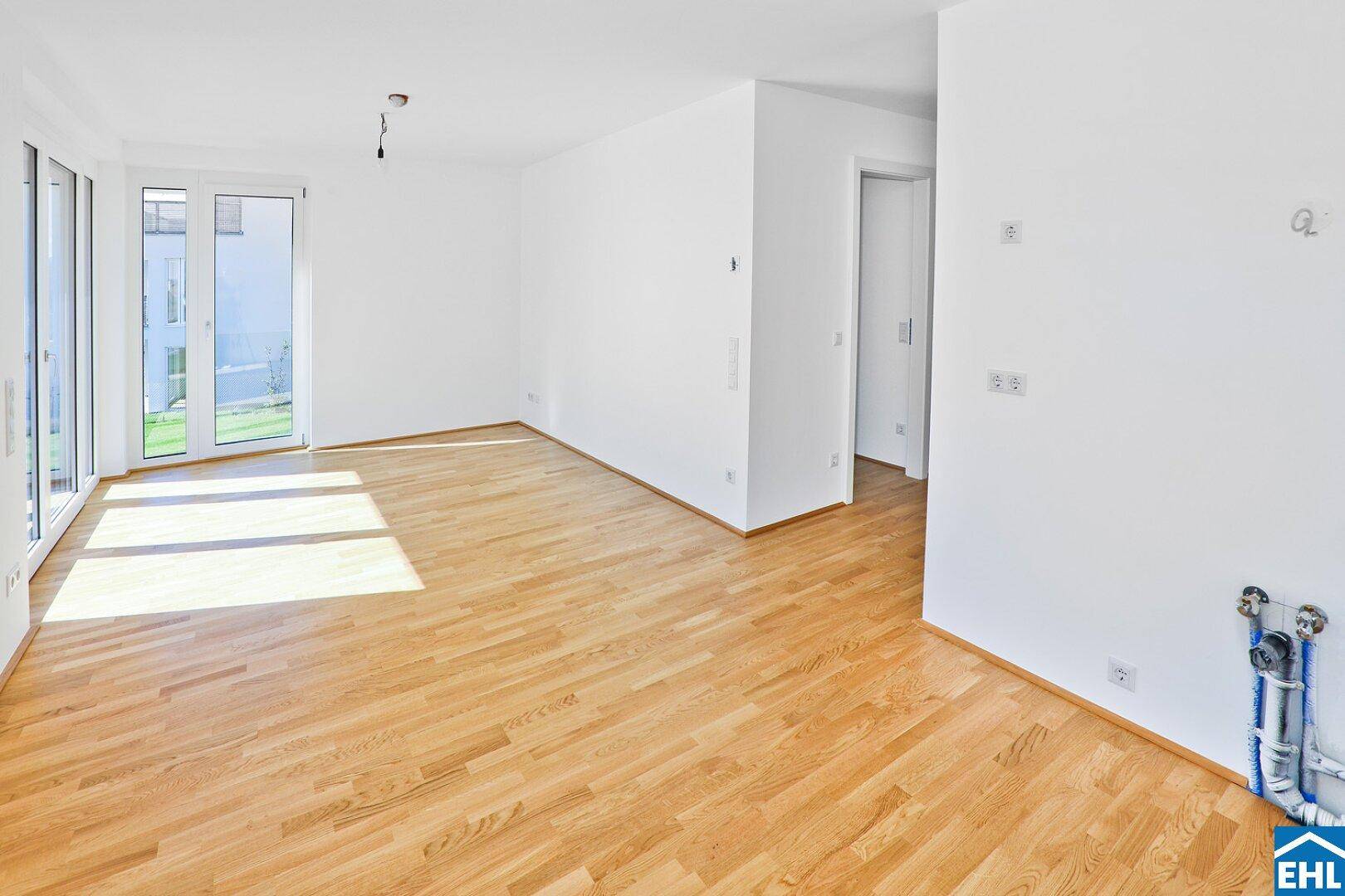 Geräumiger, heller Raum mit Holzboden und Anschlüssen für eine Küche oder Hauswirtschaftsraum.