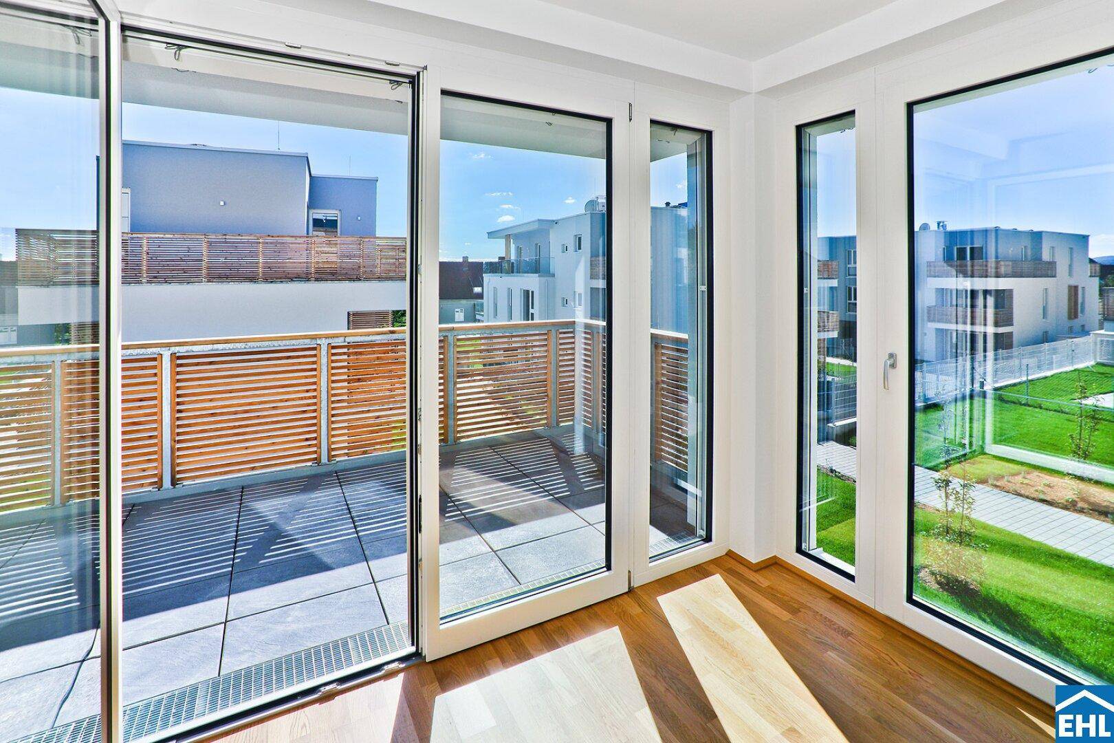Sonniger Balkon mit Holzsichtschutz, Fliesenboden und Blick auf die Umgebung.