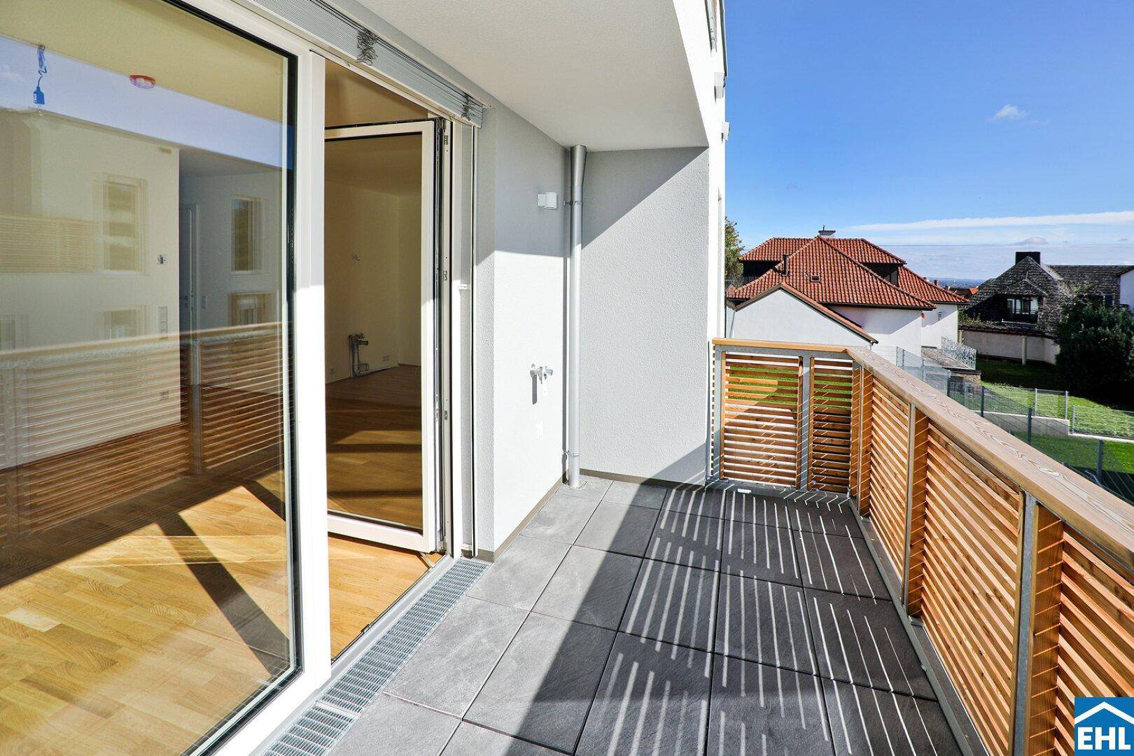 Geräumiger Balkon mit Fliesenboden, Holzsichtschutz und weitem Blick über die Dächer.